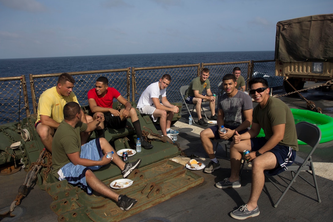 U.S. Marines and Sailors assigned to the 26th Marine Expeditionary Unit (MEU) and USS Carter Hall (LSD 50) relax out of uniform and enjoy a cookout on the flight deck of the USS Carter Hall while at sea, Aug. 31, 2013. The 26th MEU is a Marine Air-Ground Task Force forward-deployed to the U.S. 5th Fleet area of responsibility aboard the Kearsarge Amphibious Ready Group serving as a sea-based, expeditionary crisis response force capable of conducting amphibious operations across the full range of military operations. (U.S. Marine Corps photo by Cpl. Michael S. Lockett/Released)