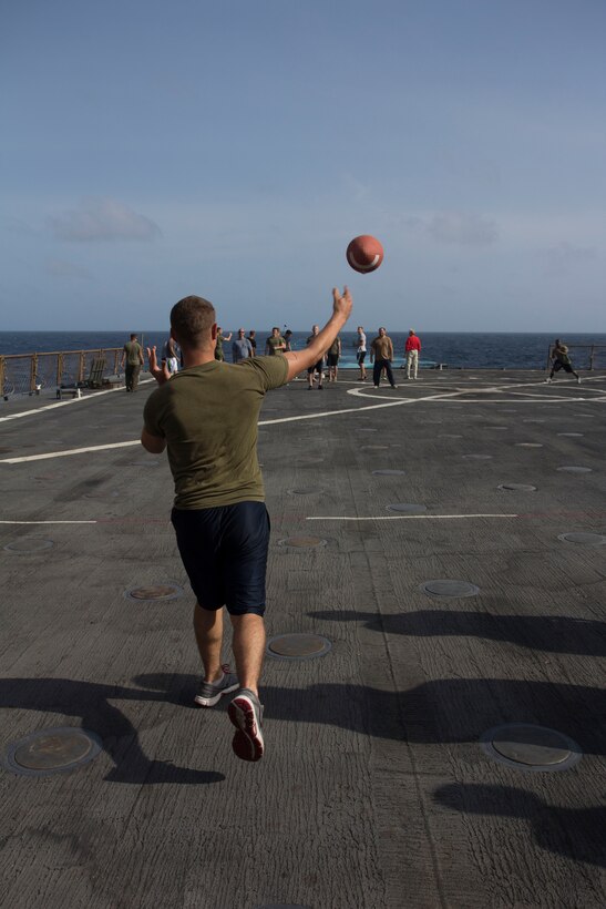 U.S. Marine Corps Lance Cpl. Brandon Carteaux, amphibious assault vehicle crewman assigned to Battalion Landing Team 3/2, 26th Marine Expeditionary Unit (MEU), tosses a football around during a cookout on the flight deck of the USS Carter Hall (LSD 50) while at sea, Aug. 31, 2013. The 26th MEU is a Marine Air-Ground Task Force forward-deployed to the U.S. 5th Fleet area of responsibility aboard the Kearsarge Amphibious Ready Group serving as a sea-based, expeditionary crisis response force capable of conducting amphibious operations across the full range of military operations. (U.S. Marine Corps photo by Cpl. Michael S. Lockett/Released)