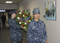 Navy service members from North American Aerospace Defense Command and U.S. Northern Command carry a wreath to a memorial following a  9-11 remembrance ceremony at NORAD and NORTHCOM headquarters, Peterson Air Force Base, Colo. Sept. 11, 2013.  In the background is a picture taken Sept. 16, 2001 of volunteer firefighters walking toward ground zero in New York City to begin their shift of rescue and recovery.   All who were involved in the search and rescue efforts of the World Trade Center collapse worked grueling hours in the hopes of finding survivors.  (U.S. Air Force Photo by Master Sgt. Andy Bellamy/Released)  