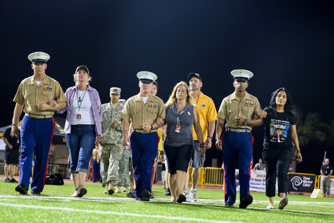 Servicemembers escort family members of Marines who sacrificed their lives with 3rd Battalion, 5th Marine Regiment, as well as Army units, during the Honor Bowl here, Sept. 7, 2013. The Gold Star family members were the guests of honor during the game and were walked to the center of the field for the coin toss. The Honor Bowl is a two-day event put together by the Honor Group to raise awareness of the sacrifices of servicemembers.