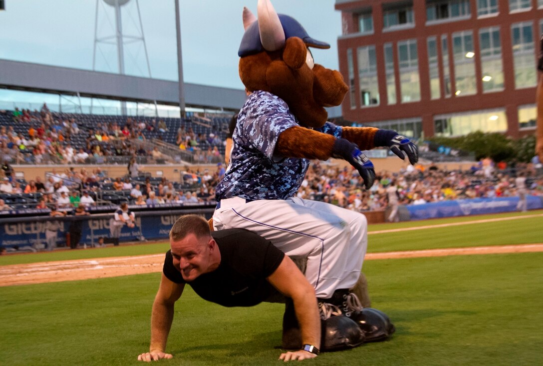 U.S. Marine Corps Sgt. Shane Otwell, a recruiter with Recruiting Sub-Station Durham, does push-ups with Wool E. Bull, the Durham Bulls mascot, on his back during a push-up competition against the mascot aboard the Durham Bull Athletic Park in Durham, N.C., August 21, 2013. Poolees of RSS Durham took their oath of enlistment in front of Durham Bulls fans before the game. (U.S. Marine Corps photo by Sgt. Dwight A. Henderson/Released)