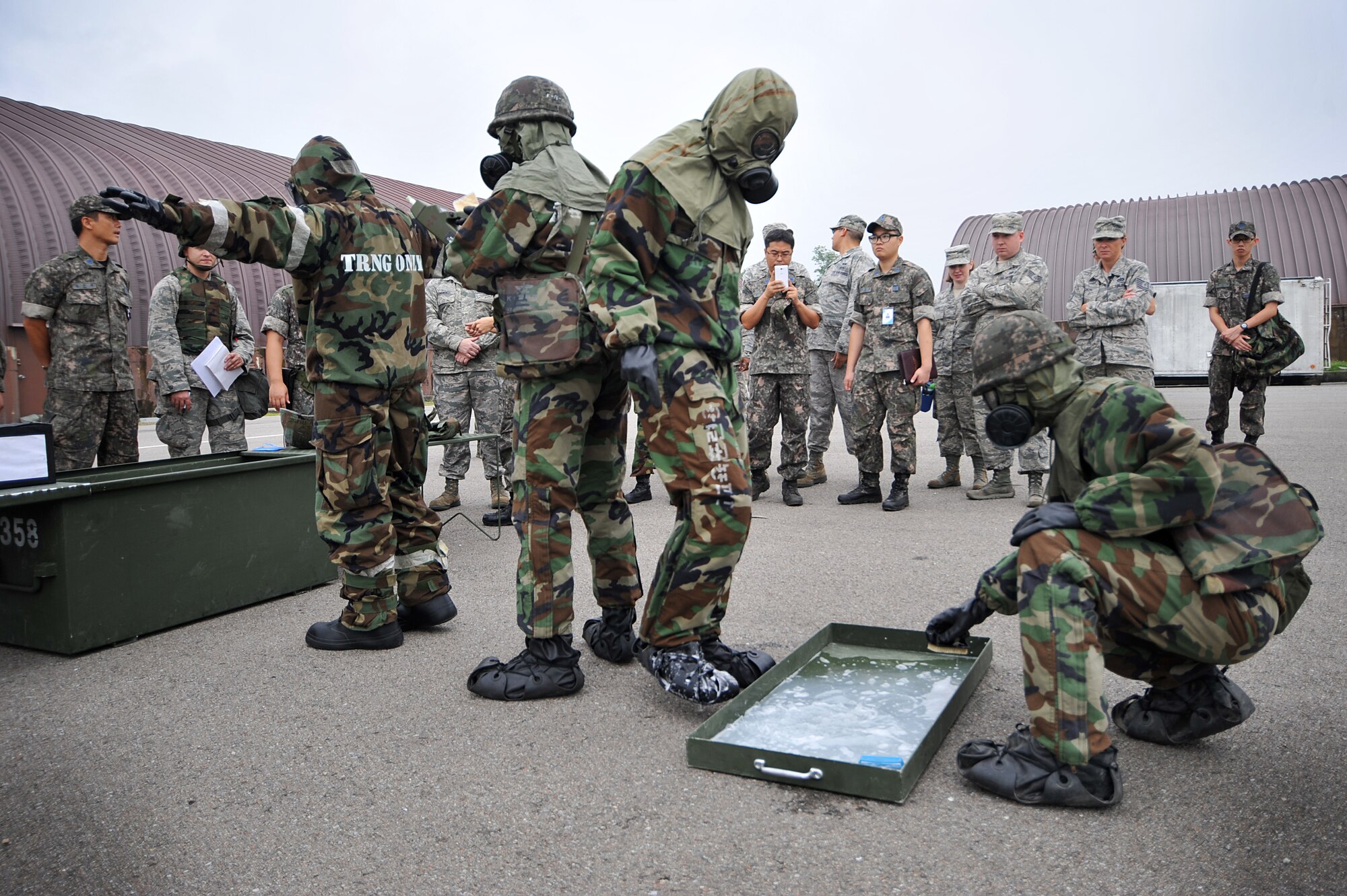 Staff Sgt. Beniteau Fenelus, left,  51st Civil Engineer Squadron emergency management readiness technician, and Republic of Korea Airmen practice contamination control area procedures during a joint chemical, biological, radiological, nuclear and explosives exercise at Osan Air Base, ROK, Sept. 12, 2013. The two organizations examined how they conduct contamination control area procedures differently and looked for improvements both sides could make.  (U.S.  Air Force photo/Staff Sgt. Emerson Nuñez)