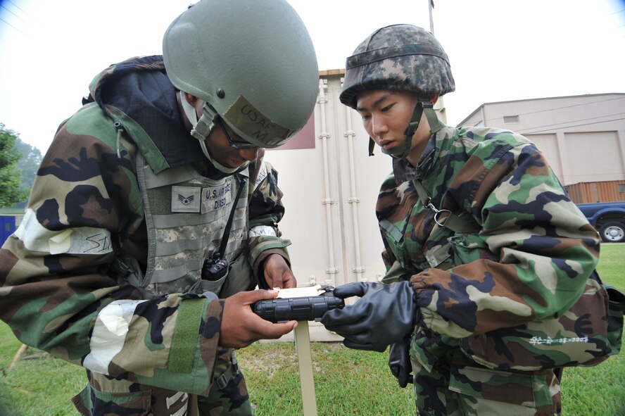U.S. Air Force Senior Airman Major Dixon, 51st Civil Engineer Squadron emergency management readiness technician, and Republic of Korea air force Senior Airman Yong Hoon Jung examine M-8 chemical detection paper during a joint chemical, biological, radiological, nuclear and explosives exercise at Osan Air Base, ROK, Sept. 12, 2013. Air Force and ROKAF CBRNE defense teams regularly train together to blend their operations and maintain a constant state of readiness. (U.S.  Air Force photo/Staff Sgt. Emerson Nuñez)