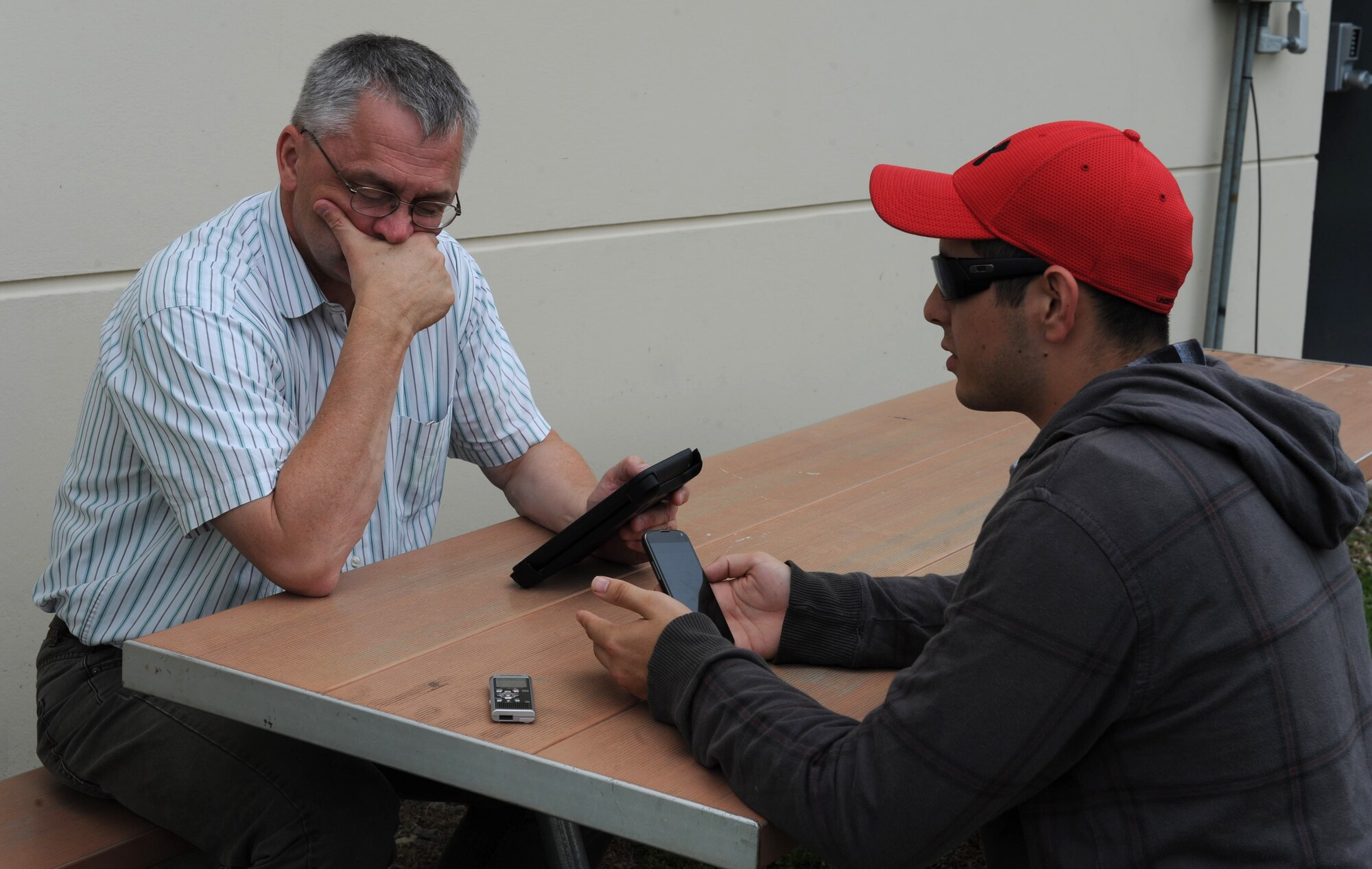 U.S. Army Lt. Col. (ret) James Moore (left), Southern Command Senior Systems engineer, and U.S. Air Force Senior Airman Kore Schmidt (right), a Joint Operations Center controller,  insert data into a cell phone and tablet, which is connected to a Web-based application that allows information sharing of mapped data by geographically dispersed participants for the purpose of improved situational awareness and decision making here, Sept. 12, 2013. Members from U.S. Southern Command and Joint Task Force-Bravo partnered with the Permanent Contingency Commission of Honduras, COPECO (the Federal Emergency Management Agency equivalent), joint efforts here and in Tegucigalpa Sept 12-15, to demonstrate and assess a mapping tool, which will improve the governmental and non-governmental organizations’ capability during complex humanitarian assistance and disaster relief operations. (Photograph released by Mr. Martin Chahin)