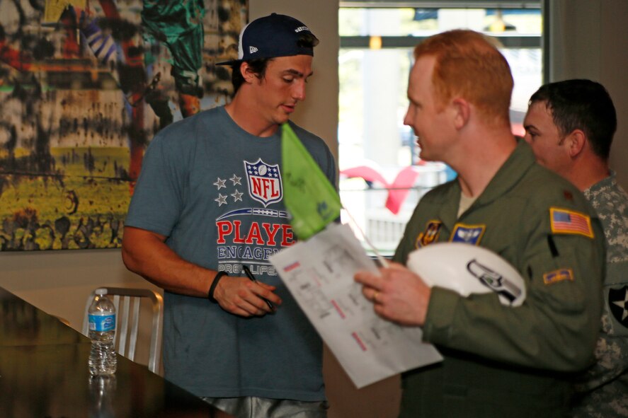 Maj. Jon Karnes, 446th Airlift Wing Flight Safety officer gets a photo signed by Seattle Seahawks tight end, Luke Wilson at the Warrior Zone, Joint Base Lewis-McChord, Wash., Sept. 10. The Seahawks officially adopted the 446th AW as their military unit of the 2013 NFL season. The Seahawks' "12th Man" flag was transferred to the 446th AW from the 4th Stryker Brigade Combat Team (SBCT), 2nd Infantry Division as part of a "change of command" ceremony. Karnes' photo was made when he was 10 years old wearing full Seahawks' memorabilia. The players had a brief meet and greet with the Airmen and Soldiers before they departed. The flag will travel with the Citizen Airman all over the world until the 2014 season. (U.S. Air Force Reserve Photo by Master Sgt. Jake Chappelle)

