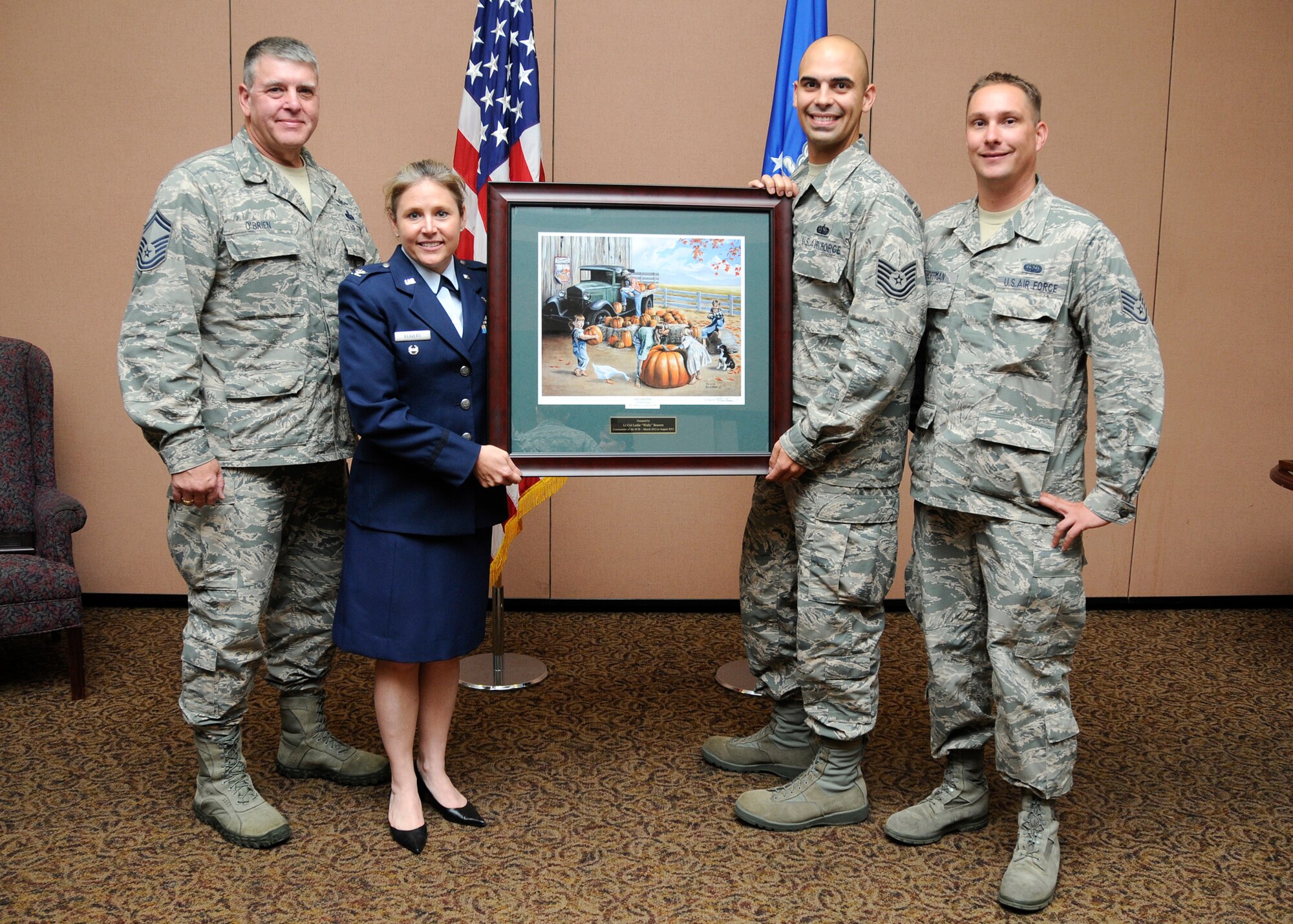 50th Intelligence Squadron members Senior Master Sgt. Norman O'Brien, Col. Leslie Beavers, Tech. Sgt. Wesely Mosure, and Staff Sgt. Jason Hoffman, hold a painting bought at a benefit auction for Senior Airman Michael Hargon, reservist with the 50th IS's communications flight, at Beale Air Force Base, Calif., Sept. 7. The Pollock Pines, Calif. painter modeled one of the children in the painting after boyhood photos of Hargon. Flight members pooled their resources at the benefit concert and auction held for Hargon and purchased the painting to display in the 50th IS building at Beale. Benefit proceeds go toward helping Hargon with his living expenses during his cancer treatment. (U.S. Air Force photo/Tech Sgt. Heather Skinkle)