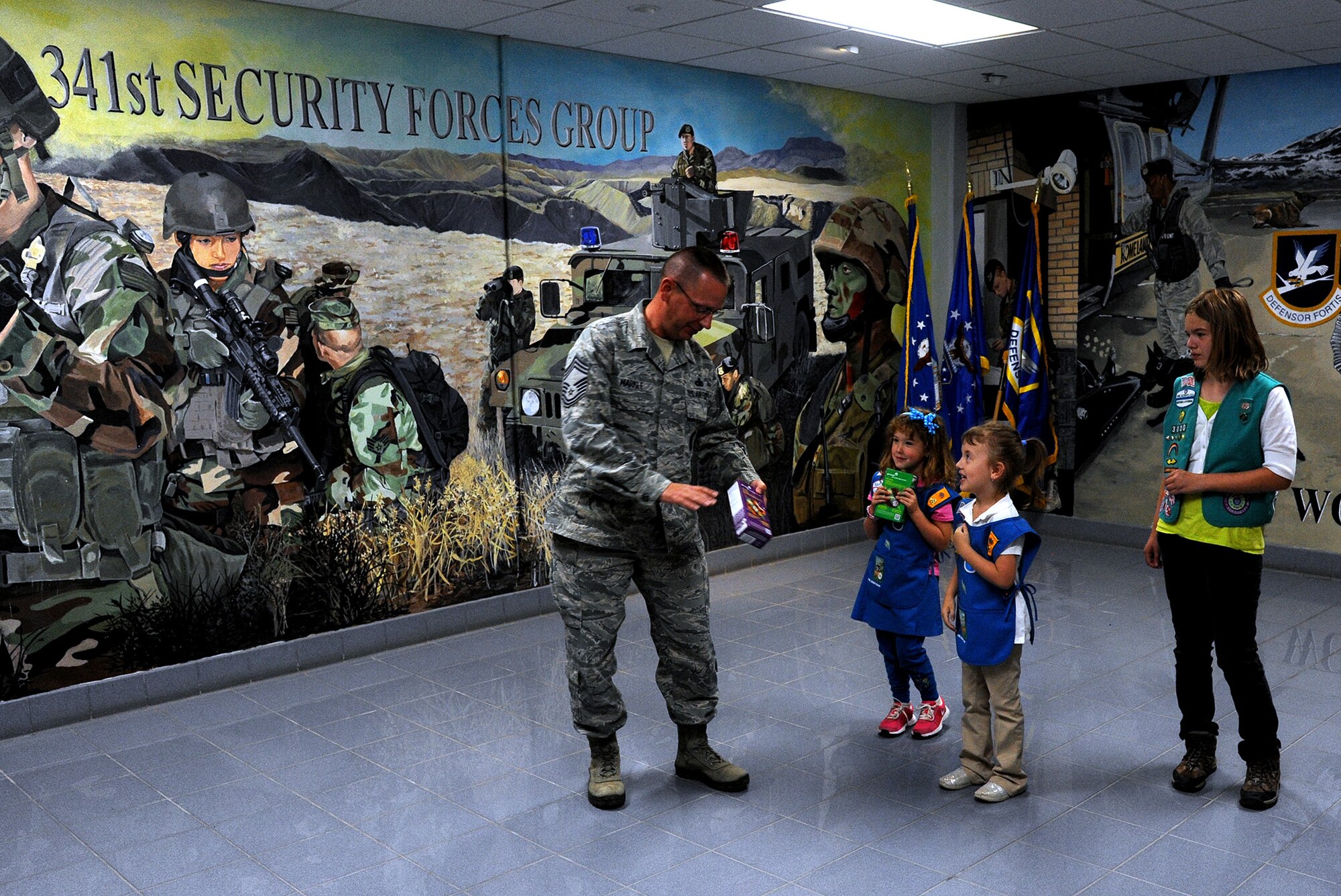 Chief Master Sgt. Allen Markle, 341st Missile Security Forces Squadron security forces manager, receives a box of Girl Scout cookies from the scouts from troops 3030, 3218 and 3500. Girl Scouts of Montana and Wyoming Council leaders encourage scouts to give back to the community every year. (U.S. Air Force photo/Staff Sgt. R.J. Biermann)