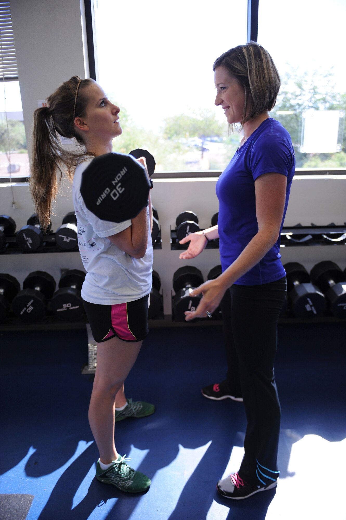 U.S. Air Force Senior Airman Katherine Sample, 355th Security Forces Squadron visitor center clerk, lifts a barbell at the Benko Fitness Center under the guidance of Kayla Pevehouse, Benko Fitness Center personal trainer, at Davis-Monthan Air Force Base, Ariz., Sept. 10, 2013. Receiving instruction, exercise or nutritional, from a licensed personal trainer can help improve physical fitness, which can help Airmen strengthen the physical pillar of Comprehensive Airman Fitness. (U.S. Air Force photo by Staff Sgt. Courtney Richardson/Released)