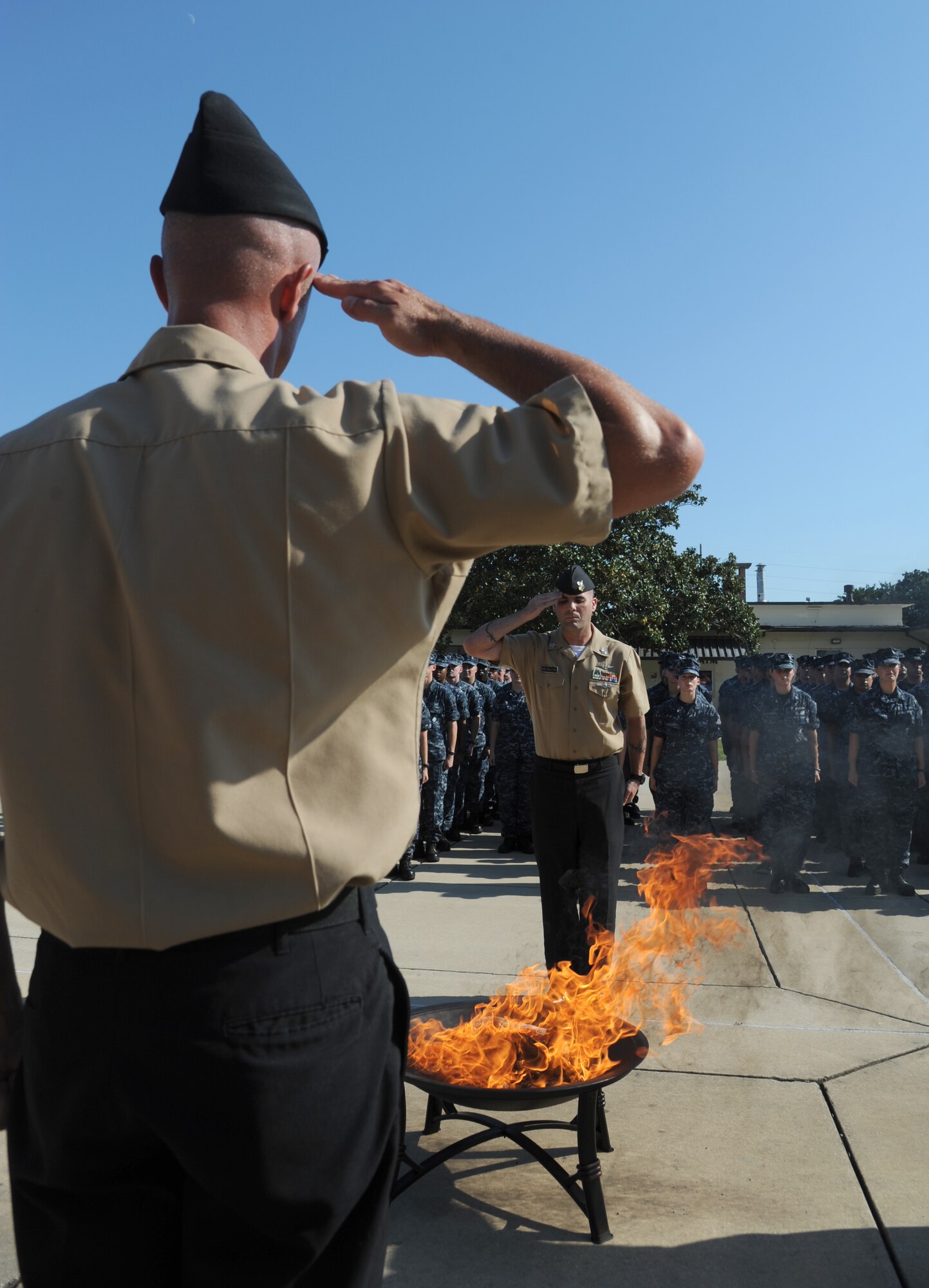 Petty Officers 1st Class Jason Bracken and Joel Seaney, Center for Naval Aviation Technical Training Unit Keesler, render a salute as a worn U.S. flag burns, which is the proper procedure for retiring a U.S. Flag, during a Sept. 11, 2013, ceremony to honor those who have given their lives since 9/11, Keesler Air Force Base, Miss.  Also in attendance were members of the Keesler Marine Corps Detachment.  (U.S. Air Force photo by Kemberly Groue)