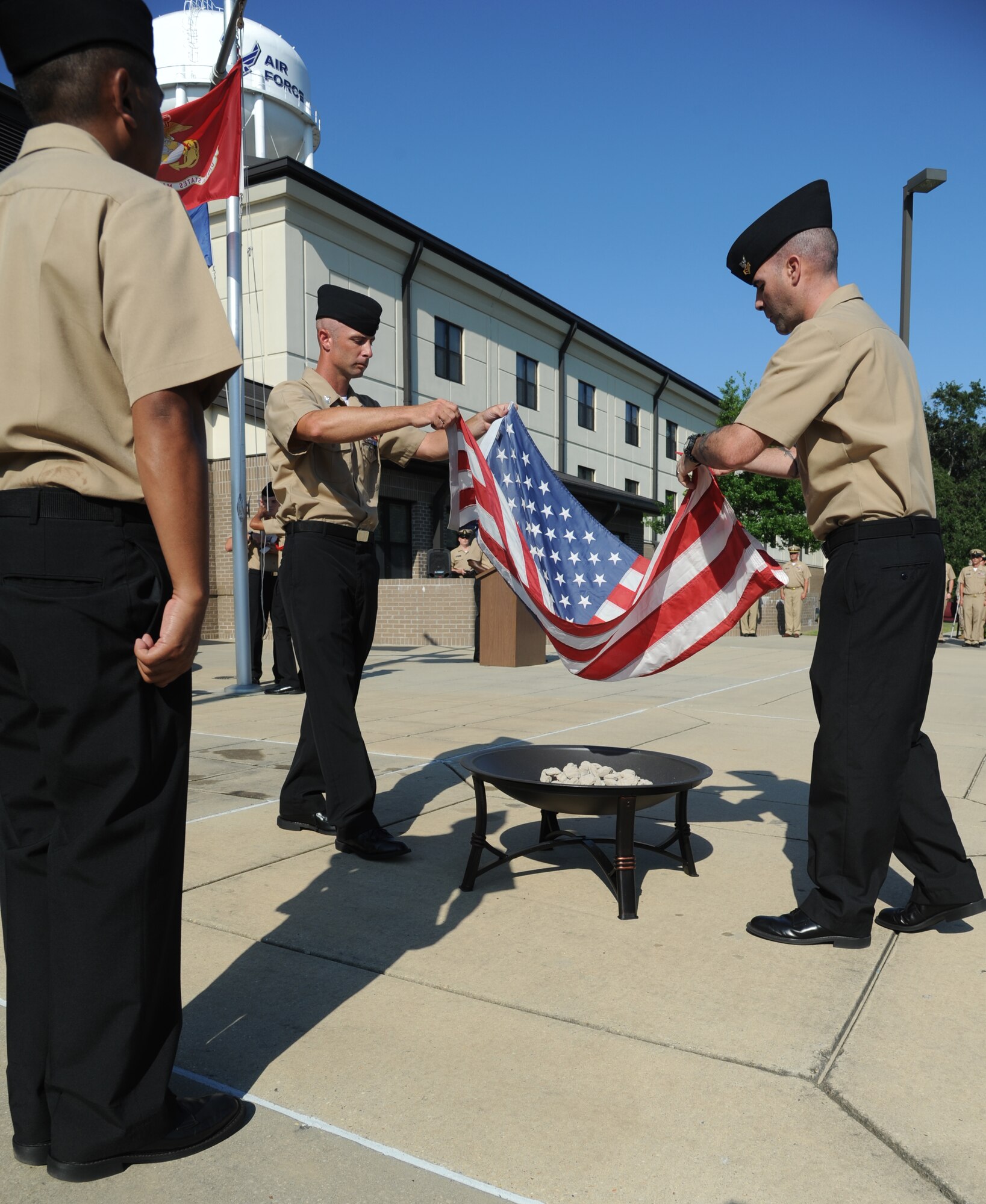 Petty Officers 1st Class Jason Bracken and Joel Seaney, Center for Naval Aviation Technical Training Unit Keesler, place a worn U.S. flag in a fire pit while following the proper procedures for retiring a U.S. Flag during a Sept. 11, 2013, ceremony to honor those who have given their lives since 9/11, Keesler Air Force Base, Miss.,  Also in attendance were members of the Keesler Marine Corps Detachment.  (U.S. Air Force photo by Kemberly Groue)
