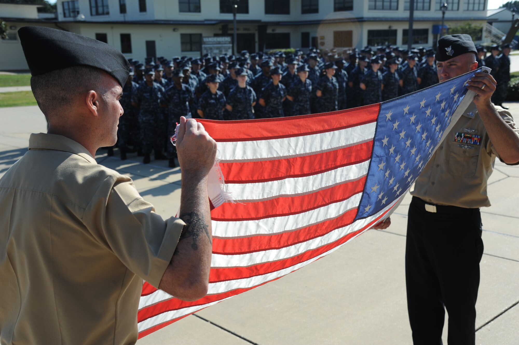 Petty Officers 1st Class Joel Seaney and Jason Bracken, Center for Naval Aviation Technical Training Unit Keesler, hold a worn U.S. flag while following the proper procedures for retiring a U.S. Flag during a Sept. 11, 2013, ceremony to honor those who have given their lives since 9/11, Keesler Air Force Base, Miss.  Also in attendance were members of the Keesler Marine Corps Detachment.  (U.S. Air Force photo by Kemberly Groue)