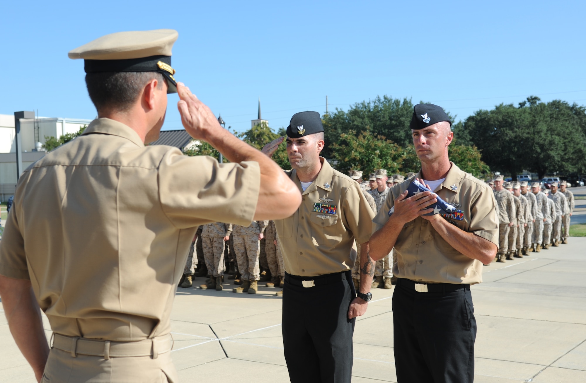 Navy Commander Jonathan Vorrath, Center for Naval Aviation Technical Training Unit Keesler commanding officer, returns a salute to Petty Officer 1st Class Joel Seaney, CNATTU, as Petty Officer 1st Class Jason Bracken, CNATTU, holds a worn U.S. flag to be retired during a Sept. 11, 2013, ceremony to honor those who have given their lives since 9/11, Keesler Air Force Base, Miss.  Also in attendance were members of the Keesler Marine Corps Detachment.  (U.S. Air Force photo by Kemberly Groue)