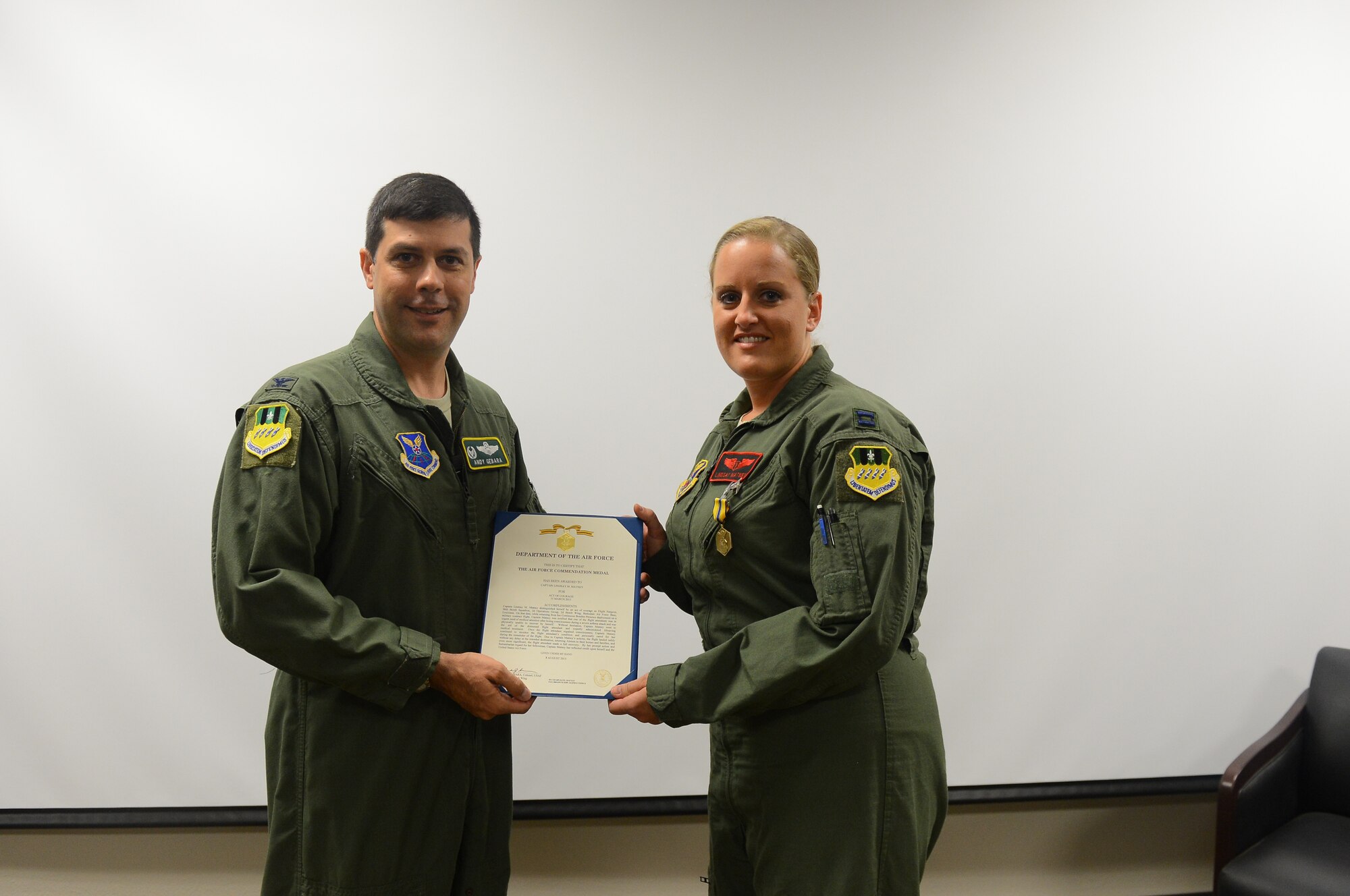 Col. Andrew Gebara, 2nd Bomb Wing commander, presents the Air Force Commendation Medal to Capt. Lindsay Matney, 96th Bomb Squadron flight surgeon, on Barksdale Air Force Base, La., Sept. 12, 2013. Matney used her skills to save the life of a flight attendant on board an aircraft en route to Alaska in March. 