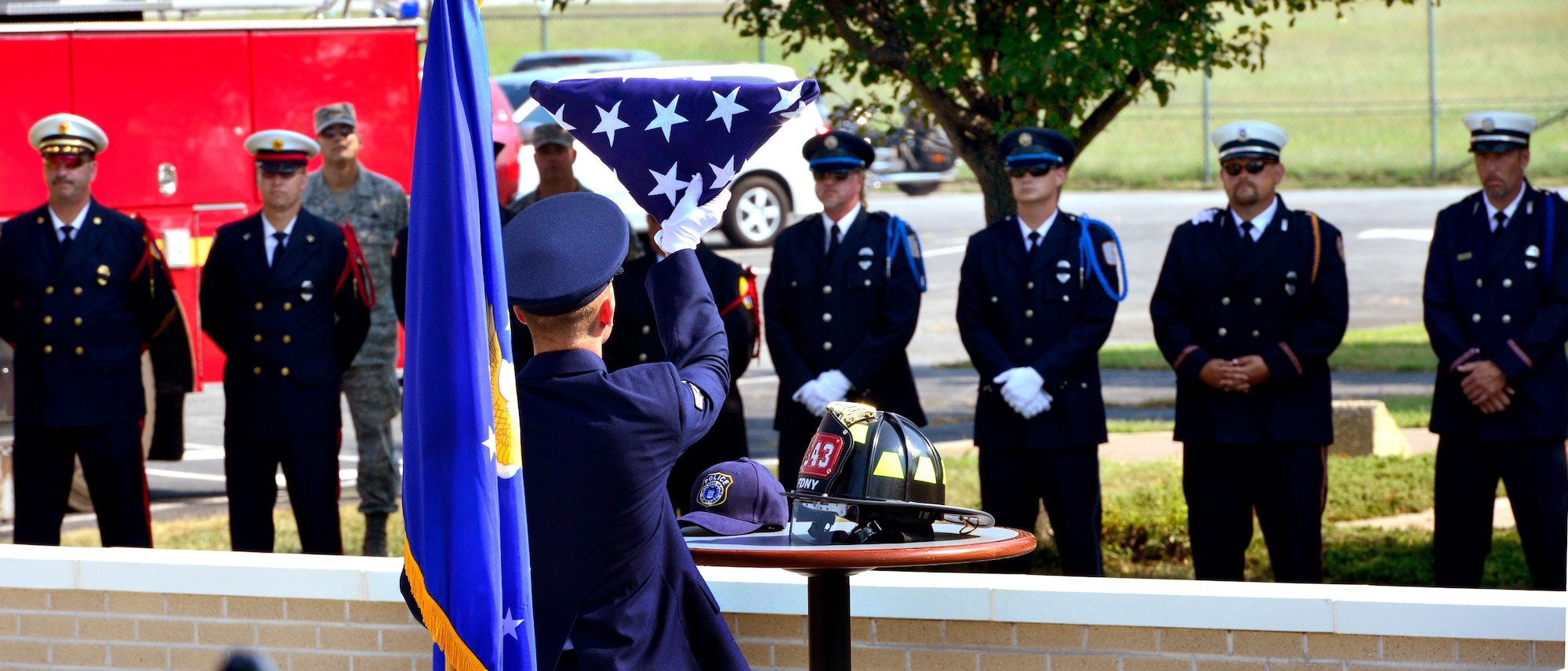 Airman 1st Class Dallas Gullion, 436th Civil Engineer Squadron fire fighter, places a folded American flag on the memorial altar at the dedication ceremony of the Sept. 11 Memorial, Sept. 11, 2013,at the Air Mobility Command Museum on Dover Air Force Base, Del. The memorial, which incorporates two pieces of steel from World Trade Center tower one, a rock from the United Airlines Flight 93 crash site and a block from the damaged portion of the Pentagon, was unveiled at the ceremony.  (U.S. Air Force photo/David S. Tucker)