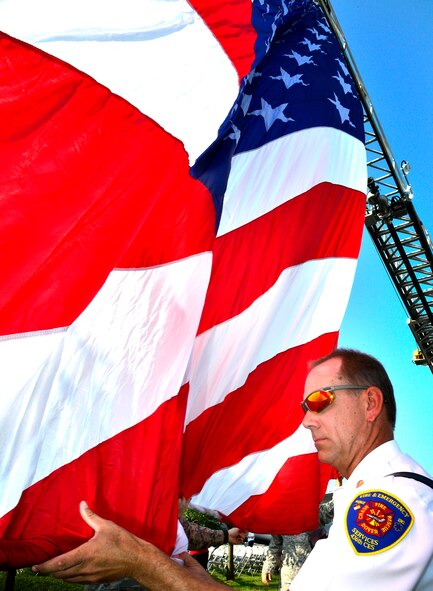 Joseph S. Mriss, 436th Civil Engineer Squadron assistant fire chief, directs the raising of the American Flag during a dedication ceremony Sept. 11, 2013, at the Air Mobility Command Museum on Dover Air Force Base, Del. A memorial, which incorporates two pieces of steel from World Trade Center tower one, a rock from the United Airlines Flight 93 crash site and a block from the damaged portion of the Pentagon, was unveiled at the ceremony. (U.S. Air Force photo/David S. Tucker) 