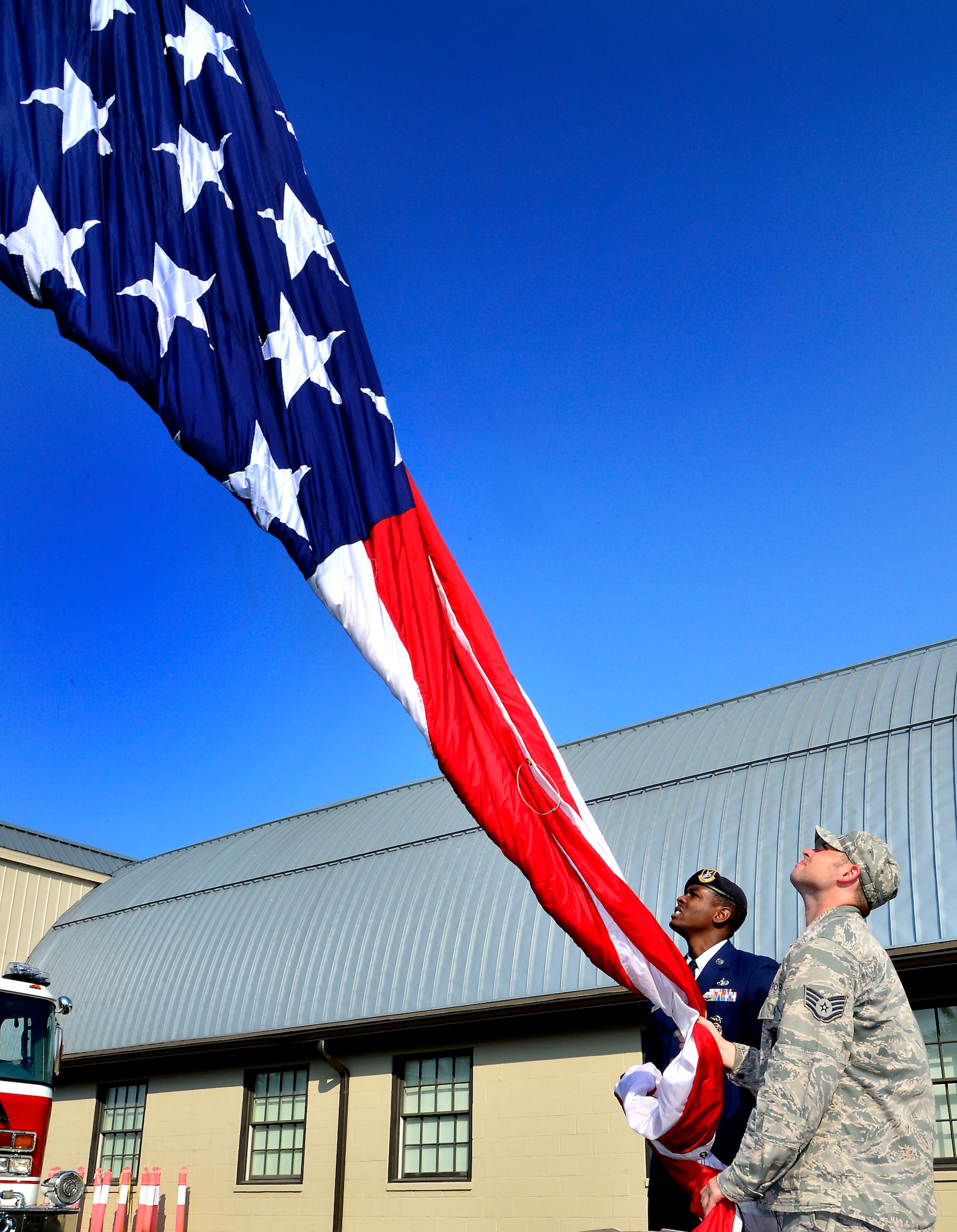 Staff Sgt. Christopher D. Houston, 436th Security Forces Squadron patrolman, and Staff Sgt. Matthew P. Varchetto, 436th Civil Engineering Squadron firefighter, raise the flag during the 9/11 Memorial dedication ceremony at the Air Mobility Command Museum, Dover Air Force Base, Del., Sept. 11, 2013. The memorial, which incorporates two pieces of steel from World Trade Center tower one, a rock from the United Airlines Flight 93 crash site and a block from the damaged portion of the Pentagon, was unveiled at the ceremony. (U.S. Air Force photo/David S. Tucker)