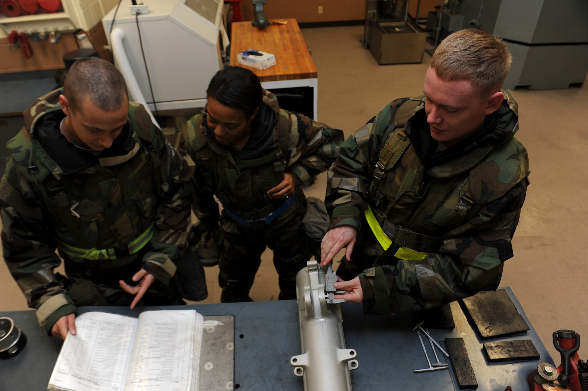 U.S. Air Force Airman 1st Class Scott Garrett, 18th Component Maintenance Squadron aircraft hydraulics journeymen, and Airman 1st Class Colin Playford, 18th CMS aircraft hydraulics apprentice, explain the measurements of an upper cylinder to Capt. Renee Cassidy, 18th CMS operations officer, during a local operational readiness exercise on Kadena Air Base, Japan, Sept. 12, 2013. The 18th Wing conducts LOREs to ensure personnel are prepared for future real world contingencies and proficient in their capabilities to provide for the common defense of the Asia-Pacific region. (U.S. Air Force photo by Senior Airman Malia Jenkins) 