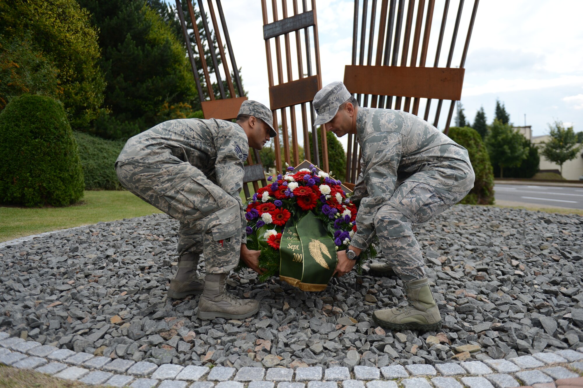 SPANGDAHLEM AIR BASE, Germany – U.S. Air Force Senior Airman David Mota, 52nd Communications Squadron military postal clerk from Queens, N.Y., and U.S. Air Force Col. David Julazadeh, 52nd Fighter Wing commander from Chillacothe, Ill.,  place a wreath in front of a 9/11 memorial during a commemorative ceremony Sept. 11, 2013. The mistress of ceremony shared the story of Mota, who was directly affected by the events that took place 12 years ago, and how his life has changed since then. (U.S. Air Force photo by Airman 1st Class Gustavo Castillo/Released)