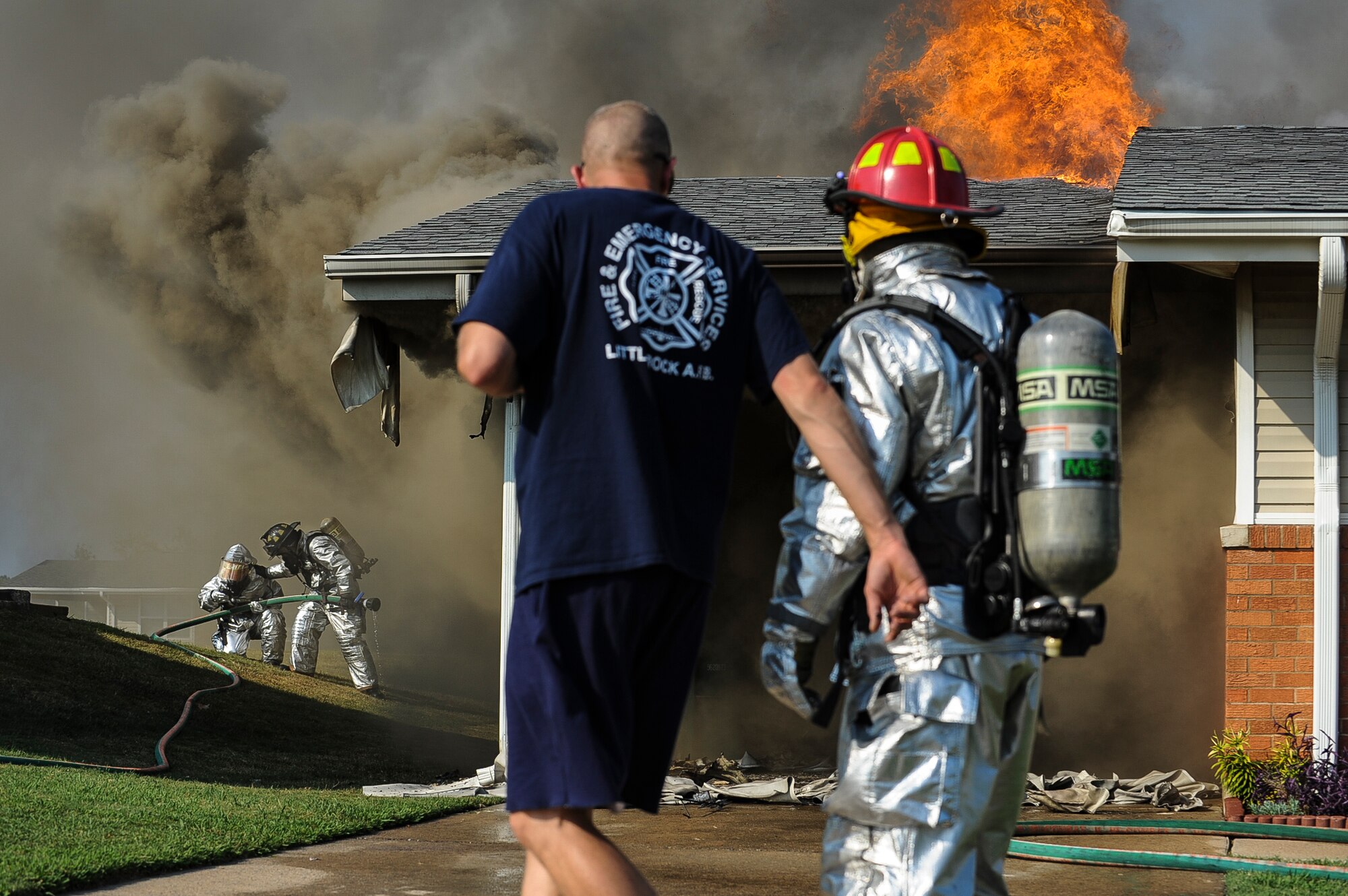 Members of the 19th Civil Engineer Squadron work together as they apply firefighting suppression techniques during a house fire Sept. 7, 2013, at Little Rock Air Force Base, Ark. The members of the 19th CES respond to approximately 800 calls a year. (U.S. Air Force photo by Airman 1st Class Cliffton Dolezal)