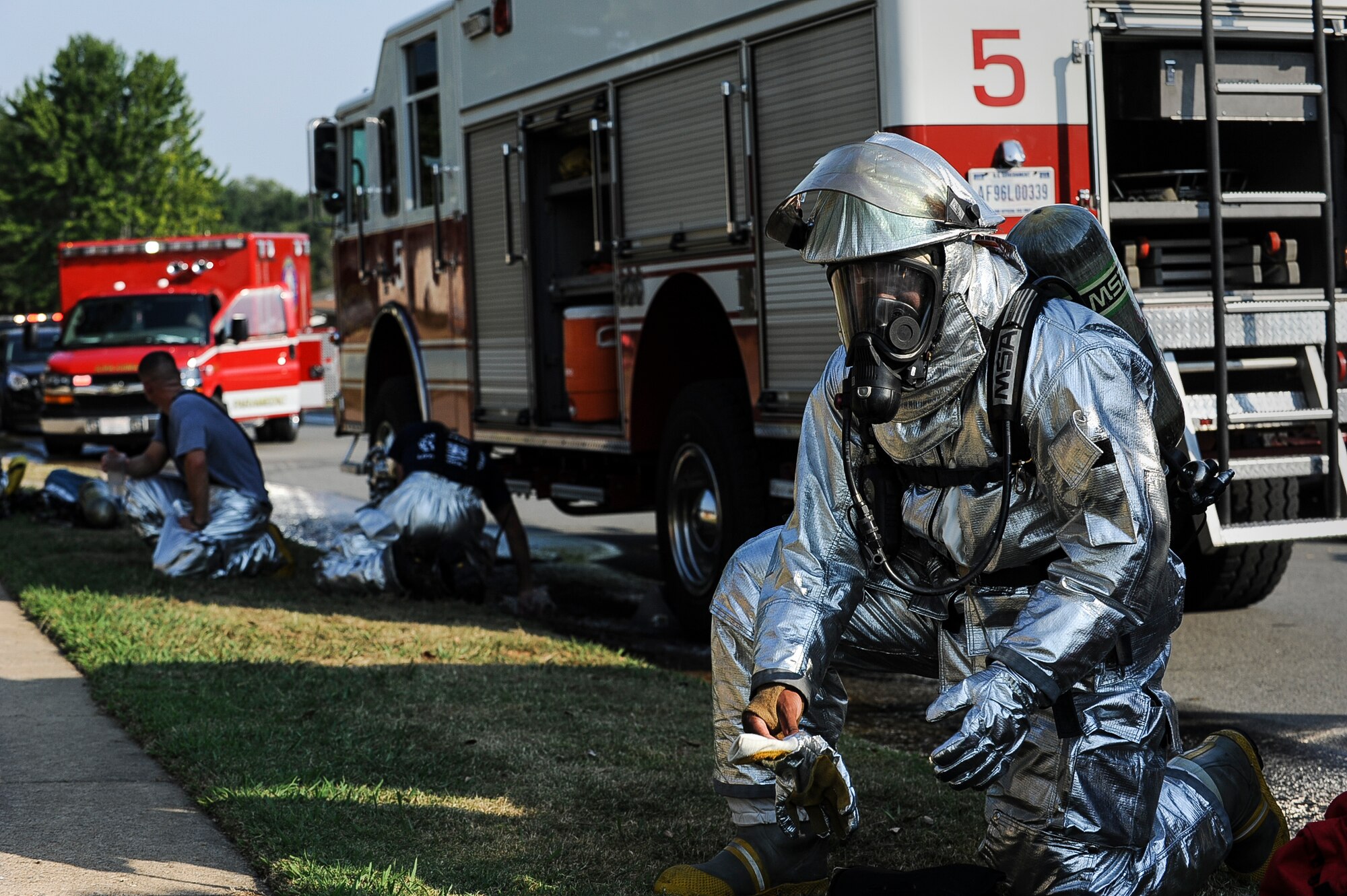 Airman 1st Class Alkenvis Allen, a 19th Civil Engineer Squadron firefighter, puts on his gloves before performing fire suppression techniques during a house fire Sept. 7, 2013, at Little Rock Air Force Base, Ark. In 2012, Little Rock AFB firefighters responded to 11 fires, only one of which was in base housing. (U.S. Air Force photo by Airman 1st Class Cliffton Dolezal)