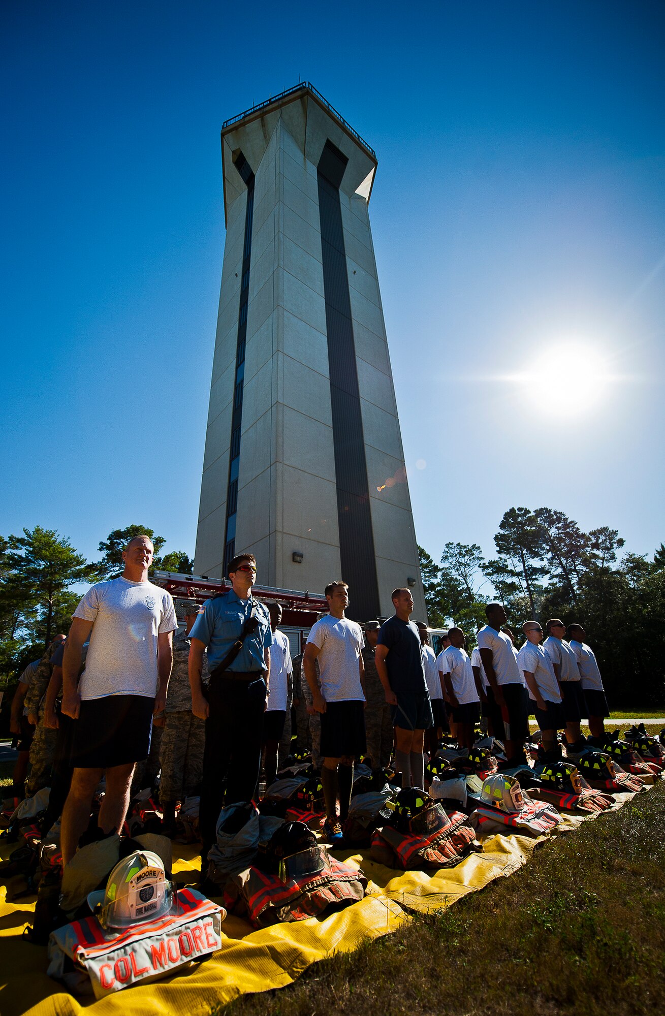 Airmen and civilian firefighters stand at attention in front of the Eglin Air Force Base control tower Sept 11 prior to their mission.  Eglin’s firefighters ascended the 11-story tower carrying ribbons with the names of the 343 firefighters killed Sept. 11, 2001. When each name was delivered to the top of the tower it was read aloud.  The event ended on top of the tower with participants hanging the ribbons over the balcony on either side of an American Flag. (U.S. Air Force photo/Samuel King Jr.)