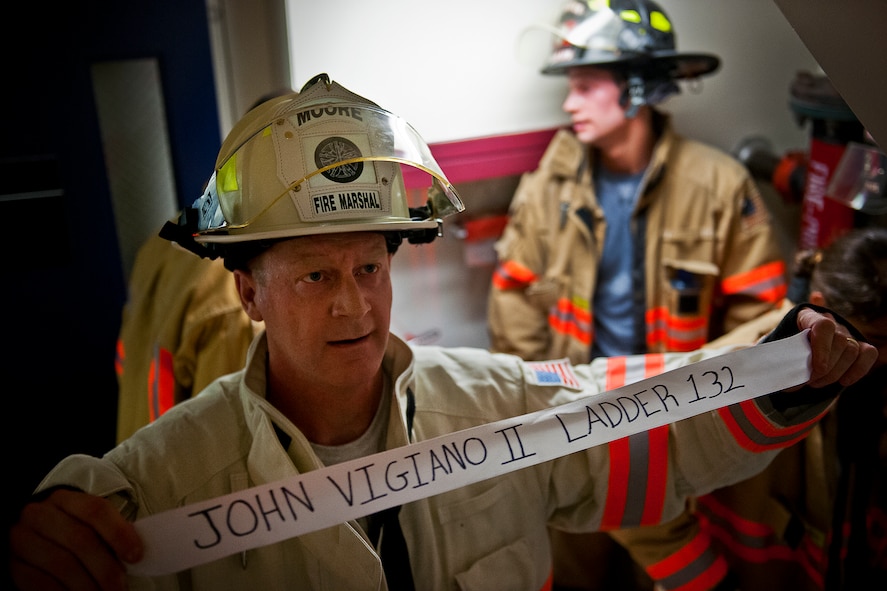 Col. Shawn Moore, the 96th Civil Engineer Group commander, presents a ribbon with a name of the 343 firefighters killed Sept. 11, 2001 after ascending to the top 11-story air traffic control tower Sept. 11. When each name was delivered to the top of the tower it was read aloud.  The event ended on top of the tower with participants hanging the ribbons over the balcony on either side of an American Flag. (U.S. Air Force photo/Samuel King Jr.)
