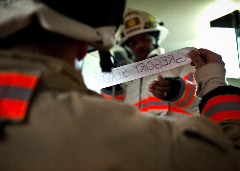 An Eglin Air Force Base firefighter presents a ribbon with a name of the 343 firefighters killed Sept. 11, 2001 to Michael Clayton, the assistant fire chief after ascending to the top 11-story air traffic control tower Sept. 1. When each name was delivered to the top of the tower it was read aloud.  The event ended on top of the tower with participants hanging the ribbons over the balcony on either side of an American Flag. (U.S. Air Force photo/Samuel King Jr.)