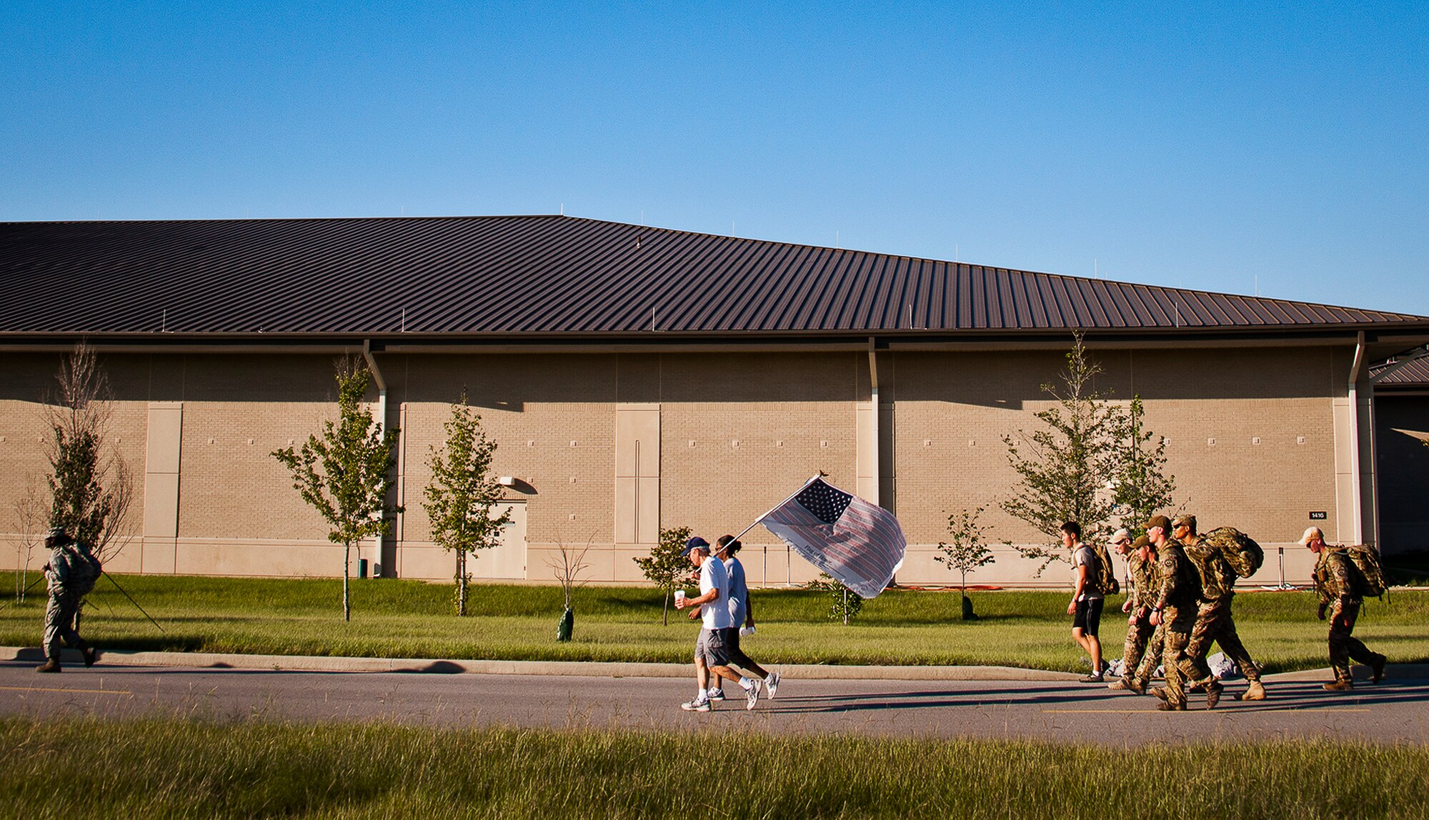 Military members and civilians walk by the F-35 academic training center during the Fallen Defender Ruck March Sept. 11 at Eglin Air Force Base, Fla.  More than 200 people came out to walk or run the 4-mile trail and pay respect to fallen security forces Airmen along the way.  (U.S. Air Force photo/Samuel King Jr.)
