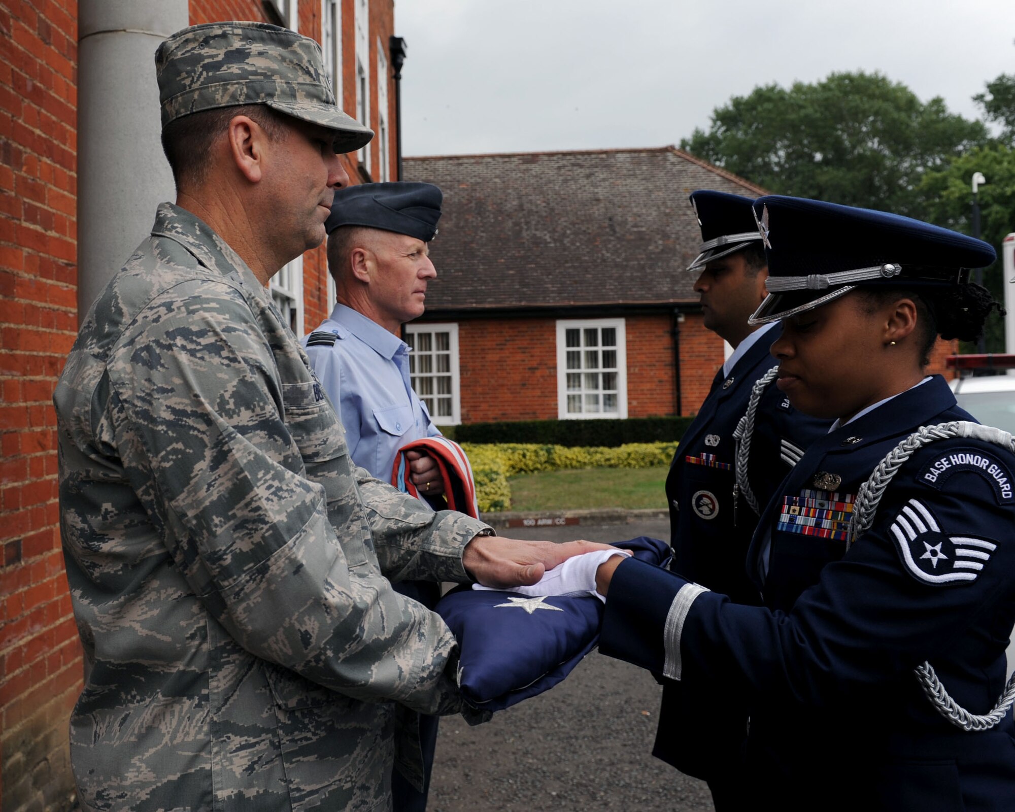 U.S. Air Force Staff Sgt. Laura Brooks, right, 488th Intelligence Squadron Help Desk client systems technician, presents a folded flag to U.S. Air Force Brig. Gen. Christopher Bence, U.S. Air Forces in Europe U.K. commander, during a retreat ceremony Sept. 11, 2013, on RAF Mildenhall, England. Retreat is a long-standing tradition honoring the flag and signaling the end of the duty day. Retreat typically takes place on the last Friday of every month, but RAF Mildenhall held a ceremonial retreat in honor of those who died in the 9/11 attacks. (U.S. Air Force photo by Airman 1st Class Preston Webb/Released)