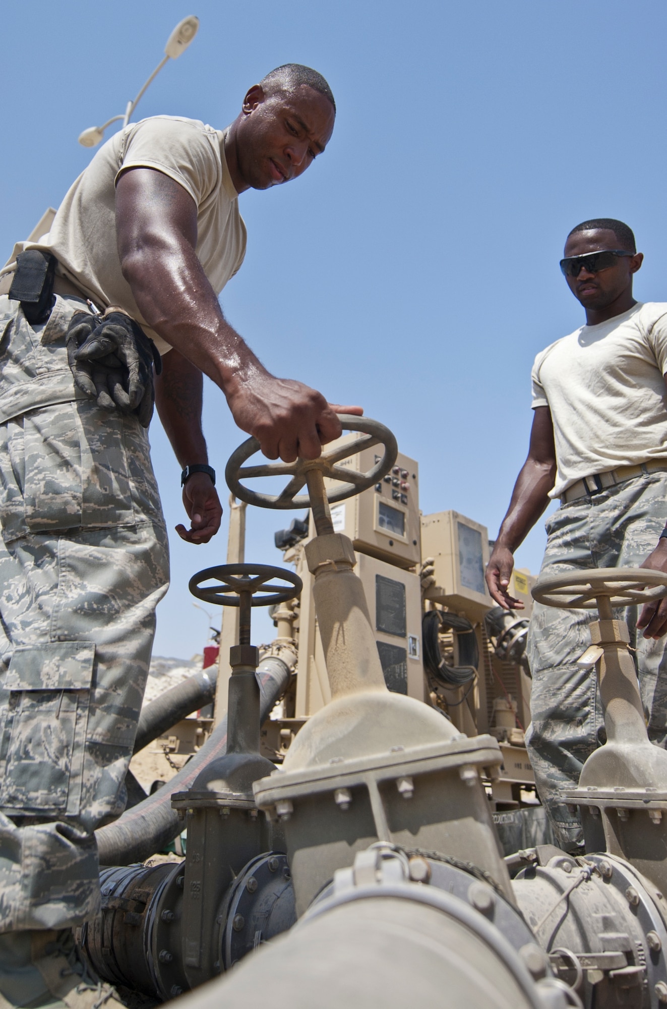 U.S. Air Force Staff Sgt. Joseph Lima, left, 380th Expeditionary Logistics Readiness Squadron fuels bulk storage supervisor, and U.S. Air Force Airman 1st Class Alec Emerson, 380th ELRS fuels storage journeyman, shut off a valve to one of the fuel bladders at an undisclosed location in Southwest Asia Sept. 3, 2013. The valves are part of a complex system routing fuel to various fuel bladders and other locations. Lima calls Bridgeport, Conn., home and is deployed from Minot Air Force Base, N.D. Emerson calls Hampton, Va., home and is deployed from Yokota Air Base, Japan. (U.S. Air Force photo by Staff Sgt. Jacob Morgan)