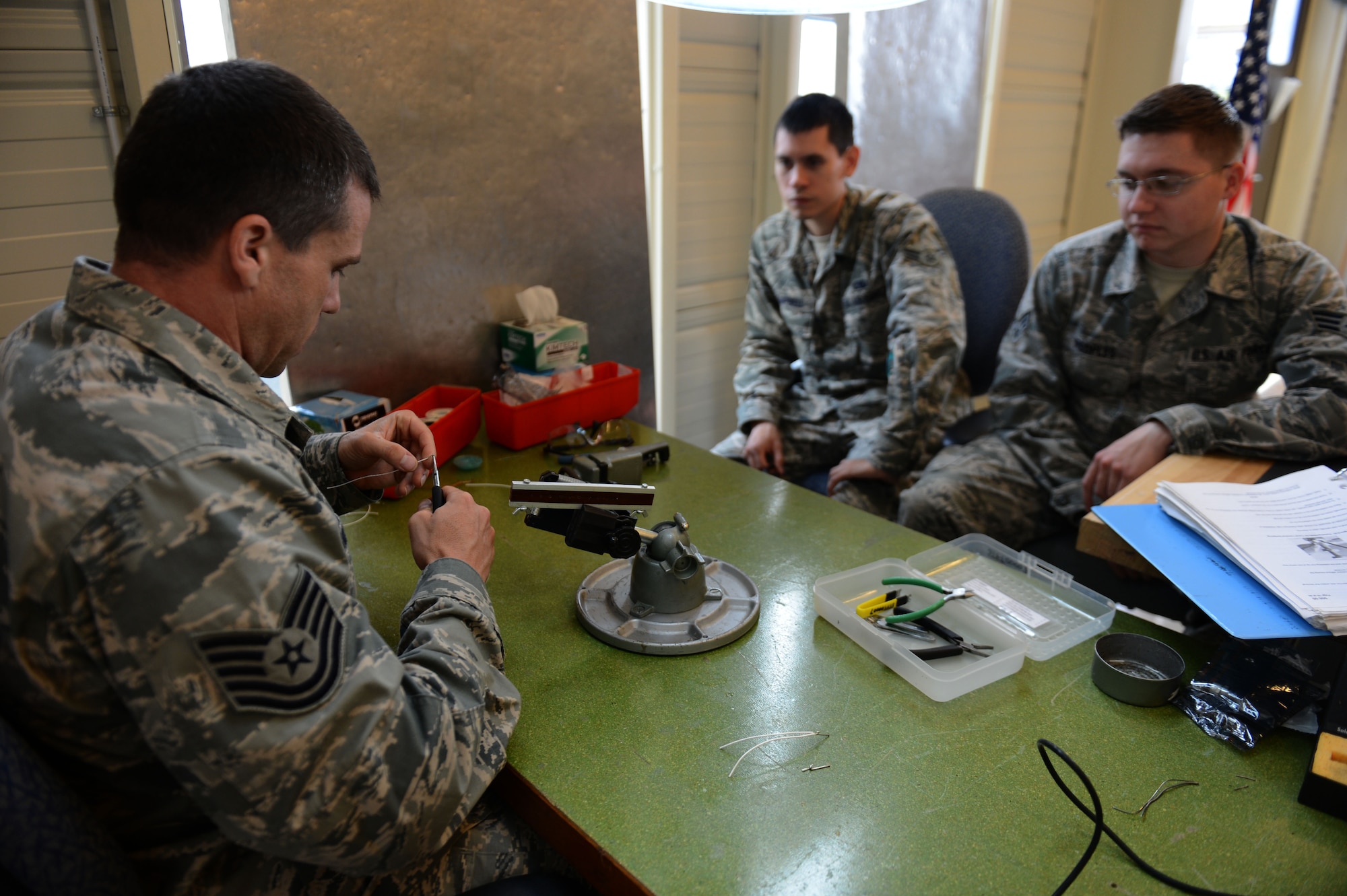 SPANGDAHLEM AIR BASE, Germany – U.S. Air Force Tech. Sgt. Mark Salzman, 372nd Training Squadron avionics instructor from Sunrise, Fla., left, demonstrates proper soldering technique for U.S. Air Force Airman 1st Class Enrique Campbell, 52nd Component Maintenance Squadron electronic warfare systems technician from Laredo, Texas, and U.S. Air Force Senior Airman Christopher Peoples, 52nd CMS electronic warfare systems technician from Mount Pocono, Pa., during a soldering class Sept. 10, 2013. The four-day course covers basic safety and risk management for soldering, along with basic soldering techniques. (U.S. Air Force photo by Airman 1st Class Gustavo Castillo/Released) 