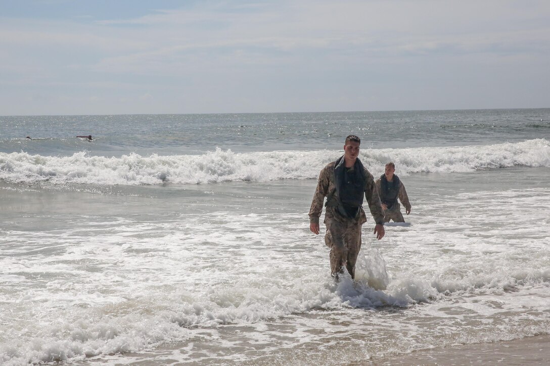 Two Marines with 2nd Assault Amphibian Battalion, 2nd Marine Division, reach shore during their annual surf qualification Sept. 12, 2013 at Onslow Beach aboard Marine Corps Base Camp Lejeune. To qualify the Marines had to swim 500 meters after evacuating an amphibious assault vehicle. 