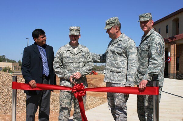CANNON AIR FORCE BASE, N.M. – (l-r): John Moreno, Albuquerque District chief of Engineering and Construction; Airman Zachariah Mick, 27th Special Operations Maintenance Squadron; Col. Tony Bauernfeind, 27th Special Operations Wing commander, U.S. Air Force; and Chief Master Sgt. Paul Henderson, 27th SOW command chief, watch as Mick prepares to cut the ribbon, officially opening the new 96-person dorm, Sept. 6, 2013.