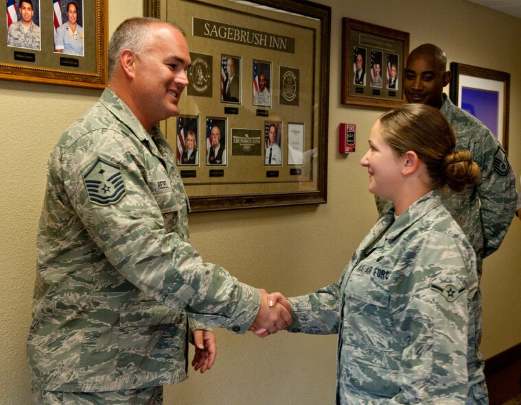 U.S. Air Force Master Sgt. Kelly Riedel, 366th Medical Group first sergeant, coins an Airman, Aug 20, 2013 at Mountain Home Air Force Base, Idaho. Riedel was so impressed with her motivation with volunteering that he presented her with a first sergeants coin. (U.S. Air Force photo by Airman 1st Class Brittany Chase/Released)