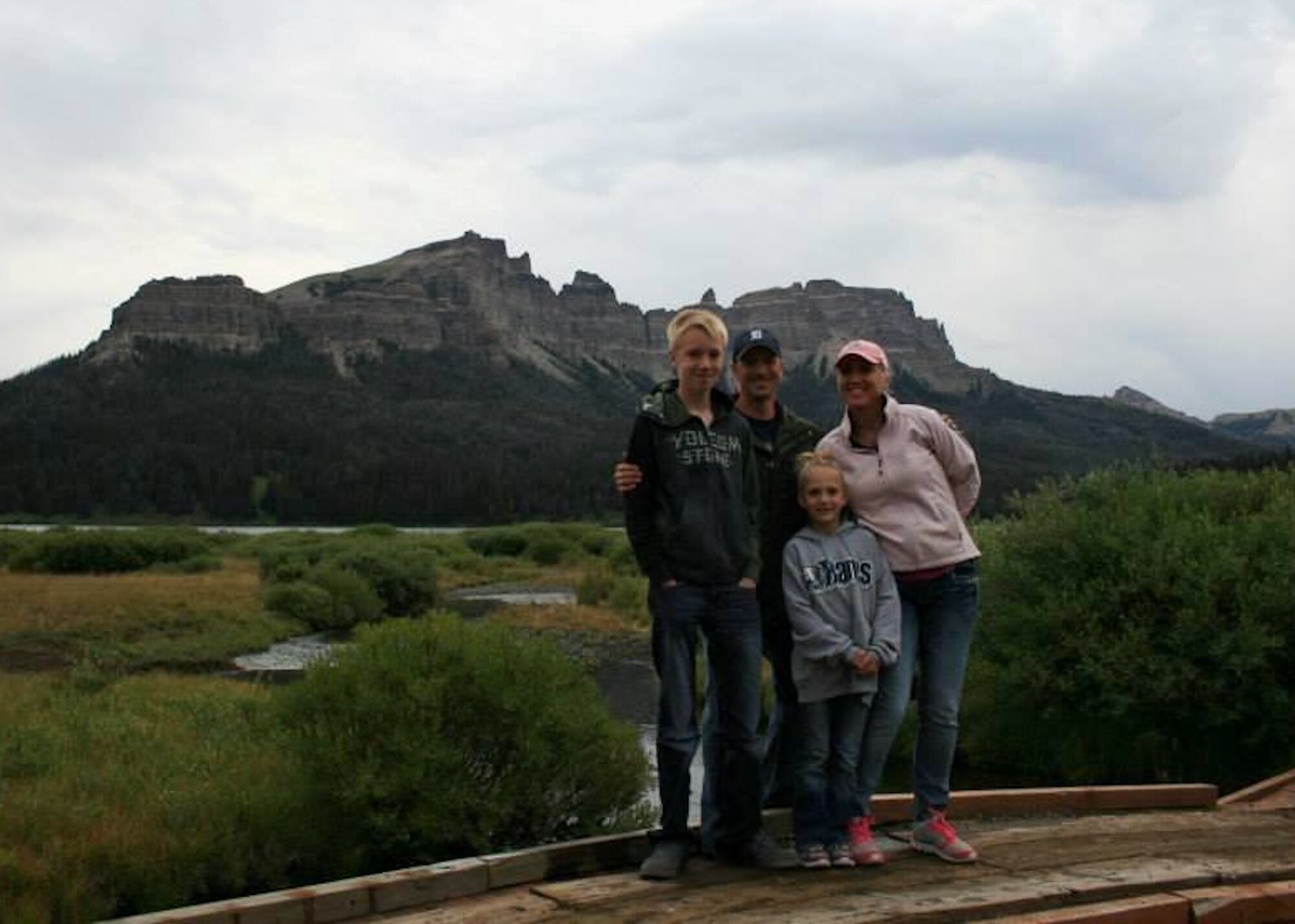 Master Sgts. Charles and Alison Bridges stand alongside their two children in front of the Pinnacle Buttes during a family vacation in the Teton National Forest, W.Y., Aug. 16, 2013. On their way home, they witnessed a paragliding accident and administered first-aid to the injured victim. (Courtesy photo by Allison Bridges)