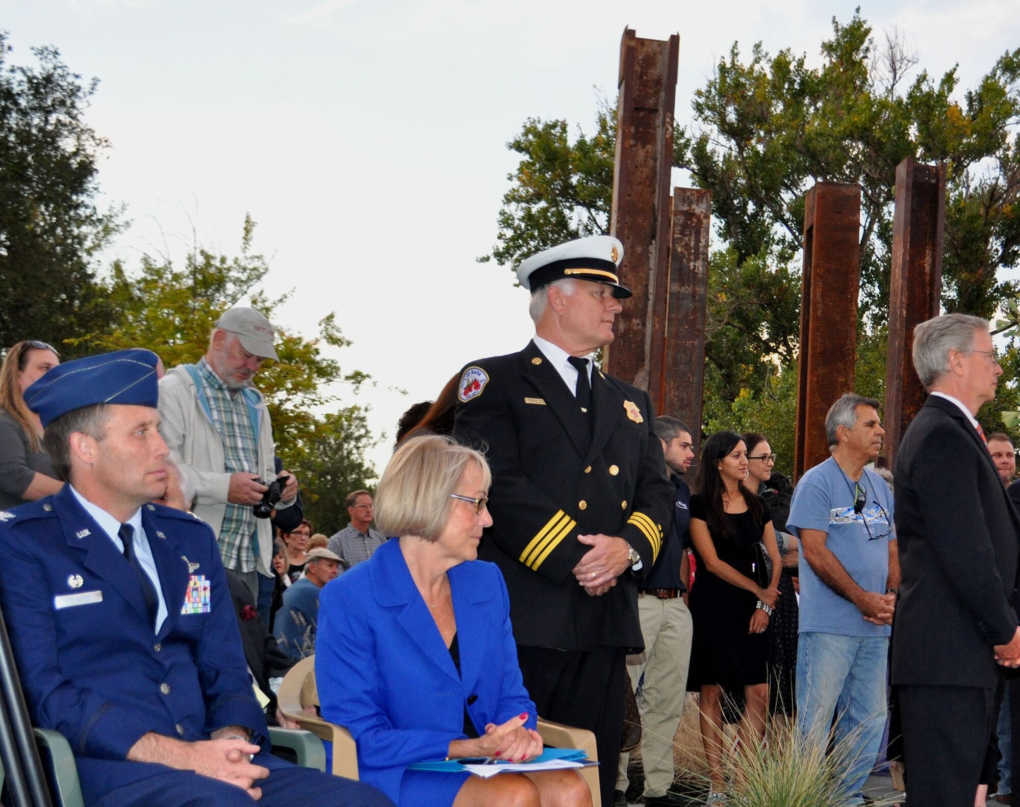 TRAVIS AIR FORCE BASE, Calif. -- The Napa Memorial Garden was dedicated downtown. Attending the dedication was Col. Matthew Burger, commander of the Reserve's 349th Air Mobility Wing, Travis Air Force Base, Calif. Here, he is seated next to his Honorary Commander, the Mayor of Napa, the Honorable Jill Techel. Standing behind the Mayor is Napa Fire Marshal Darren Drake, who is responsible for getting the project started when he asked for one beam from the World Trade Center twin towers. He and Napa artist Gordon Huether, who designed the sculptural part of the garden, were given five beams. Four of the 24-foot tall steel beams can be seen here, with other smaller beams throughout the garden. Huether designed four panels of glass that stand at its center. With the largest reaching more than 14 feet into the air, the panels display the names of every victim, with one telling the story of that fateful day, and also explaining why Napa built this memorial. More than 500 people attended the dedication. (U.S. Air Force photo/Ellen Hatfield)