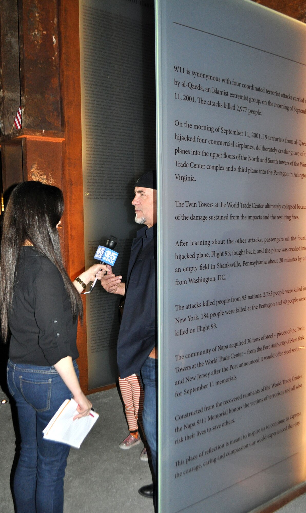 TRAVIS AIR FORCE BASE, Calif. -- Napa artist Gordon Huether is interviewed by a local television reporter at the unveiling of the Napa 9-11 Memorial Garden. With the help of Napa Fire Marshal Darren Drake, Huether secured five beams from the ruins of the World Trade Center to incorporate into his sculture for the garden. The glass panels that he created to anchor the beams bear the names of each victim of the terrorist attacks of Sept. 11, 2001. Several Travis AFB leaders attended the dedication, including Col. Matthew Burger, Commander of the Reserve's 349th Air Mobility Wing. He accompanied Napa Mayor Jill Techel, who serves as his Honorary Commander. (U.S. Air Force photo/Ellen Hatfield)