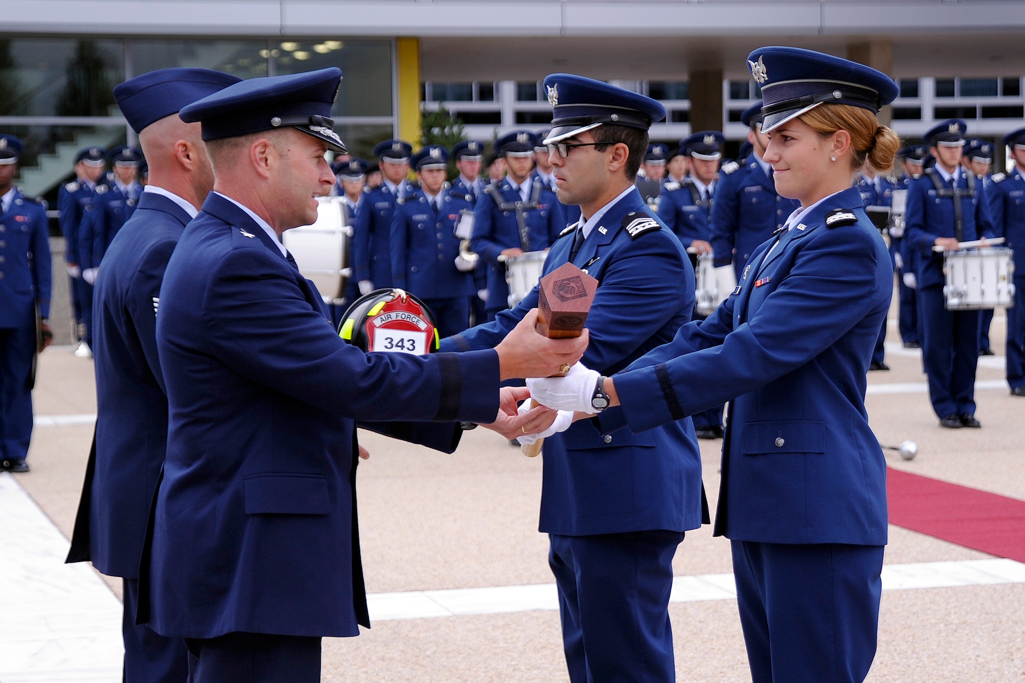 Academy Commandant of Cadets Brig. Gen. Gregory Lengyel, (front, left) and Tech. Sgt. Jason Linta, a 10th Civil Engineer Squadron firefighter, are presented a memorial baton and firefighter's helmet by Cadet 1st Class Jennifer Johnsen (right) and Cadet 2nd Class Louis Fasano, to be carried by the cadets during the 9/11 Remembrance Run on the Academy’s Terrazzo Wednesday. (U.S. Air Force Photo/Mike Kaplan)