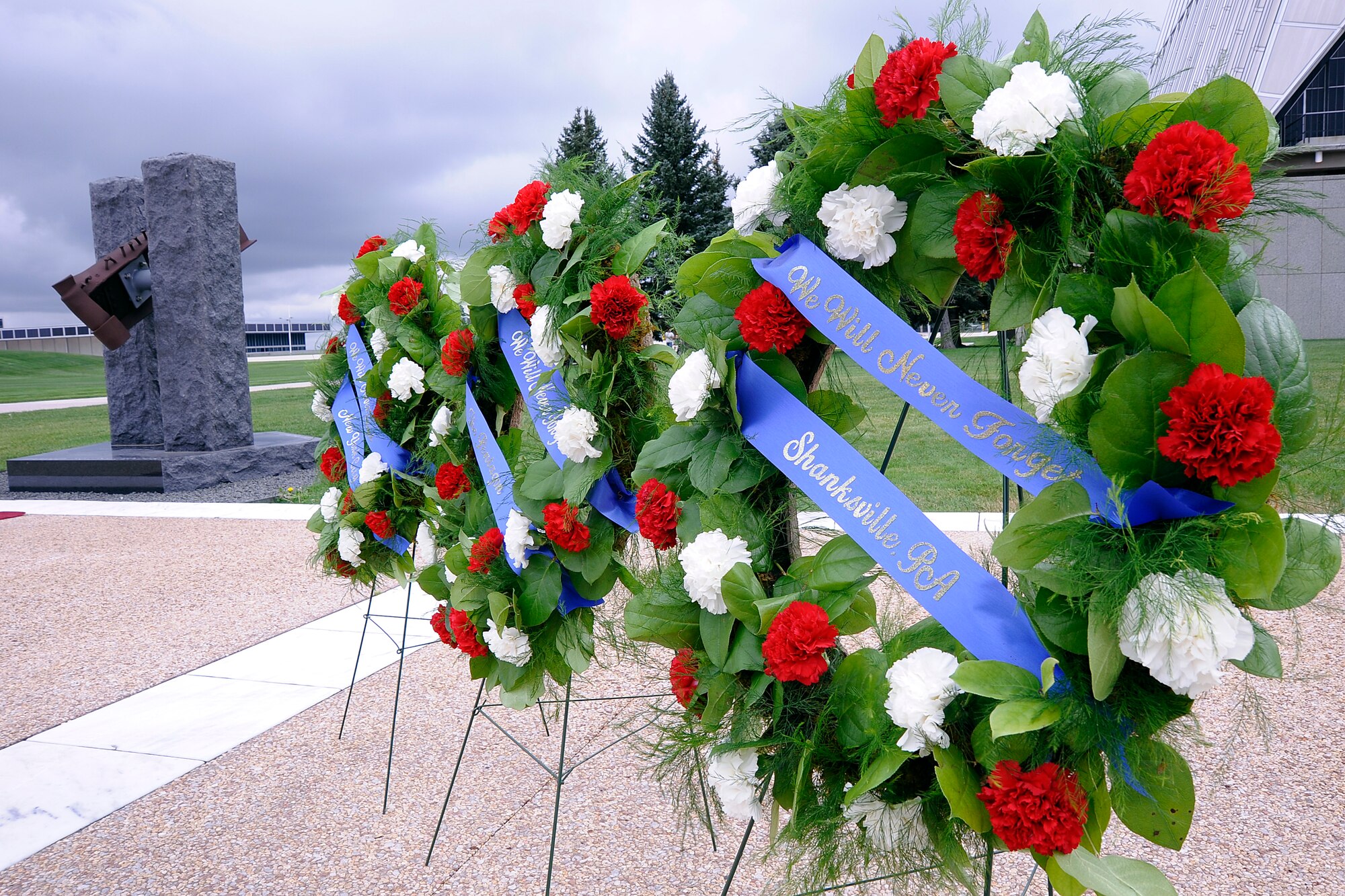 Ceremonial wreaths are displayed by the 9/11 Memorial at the  9/11 Remembrance Ceremony on the Academy’s Terrazzo. The memorial was dedicated on Sept. 11, 2011 by the Academy class of 1976 to commemorate the 10th anniversary of the attacks on the nation. The two towers represent the World Trade Center towers, the platform is the shape of the Pentagon and the beam through the center is from WTC Tower Two. The base inscriptions include Shanksville, Pa., along with The Pentagon and The World Trade Center. (U.S. Air Force Photo/Mike Kaplan)