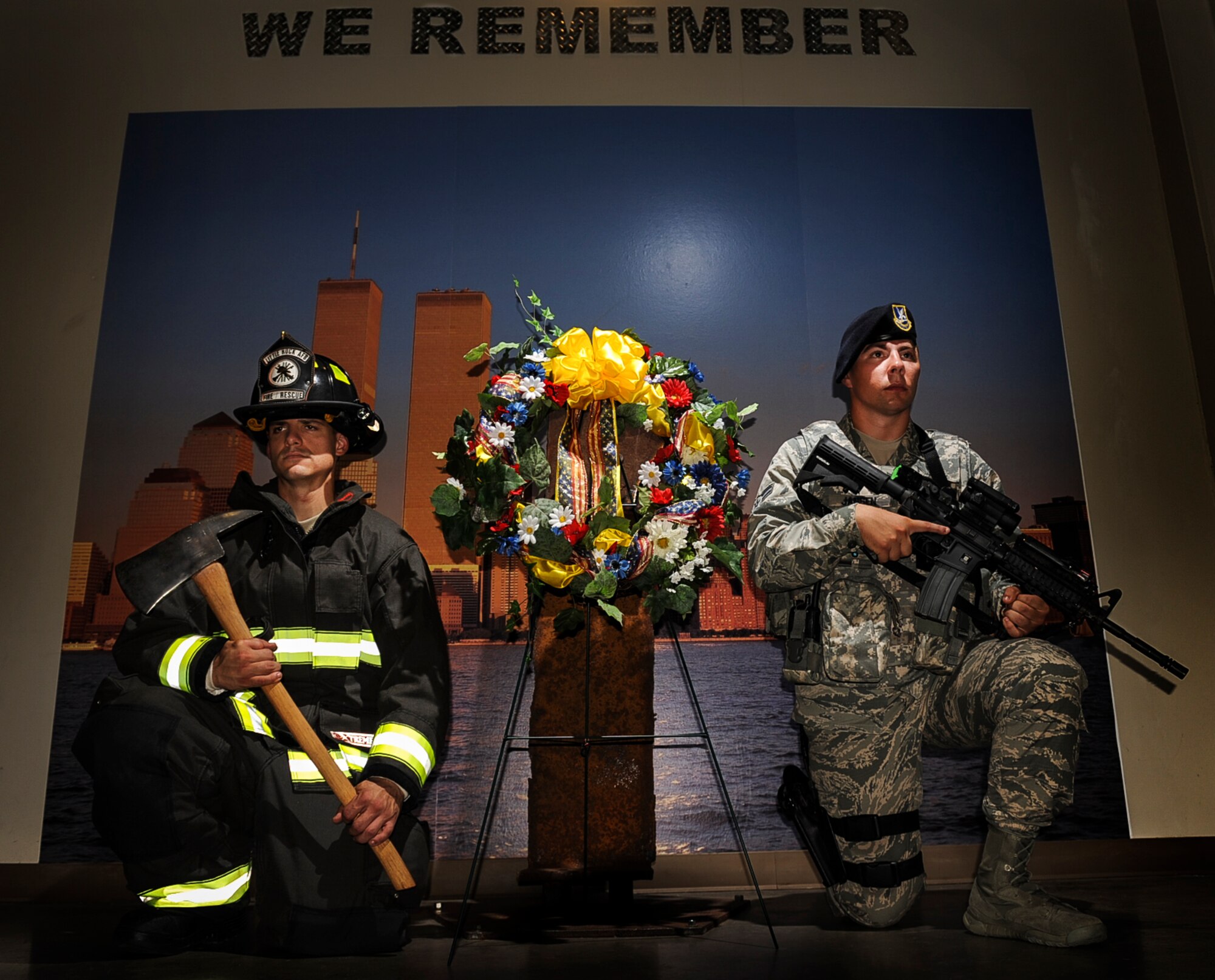 Staff Sgt. Zach Colburn, a 19th Civil Engineer Squadron firefighter, and Airman 1st Class Kyle Jensen, a member of the 19th Security Forces Squadron, kneel beside a wreath placed in remembrance of those whose died on 9/11, Sept. 11, 2013, at Little Rock Air Force Base, Ark. Chief Master Sgt. Margarita Overton, 19th Airlift Wing command chief, and Chief Master Sgt. Andrea Gates, 314th Airlift Wing command chief, placed the wreath in front of a recovered I-beam from the Twin Towers. (U.S. Air Force photo by Airman 1st Class Cliffton Dolezal) 