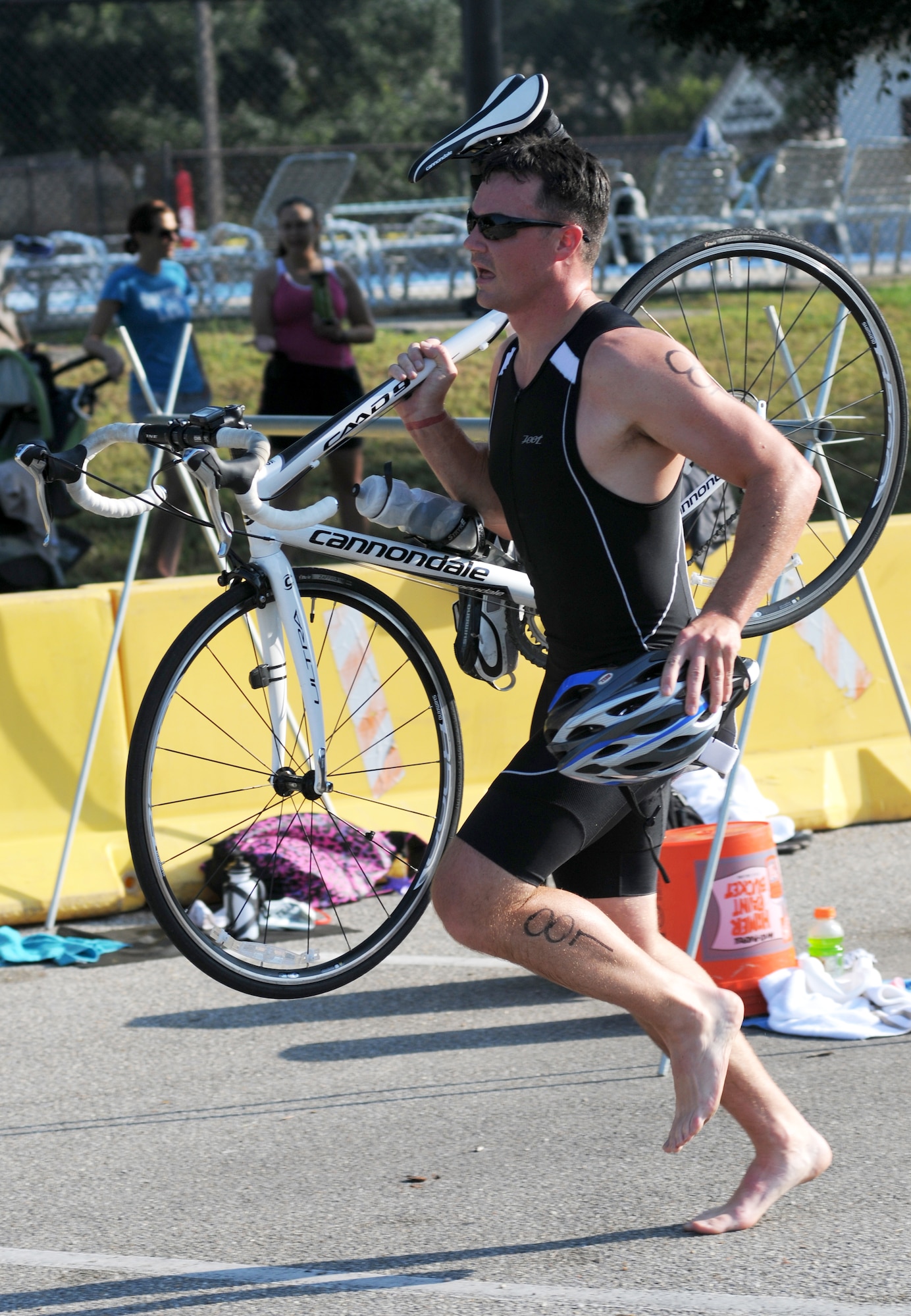 Dominick Martin, 335th Training Squadron, carries his bike as he transitions from cycling to running during Keesler's mini-triathlon Sept. 13, 2013, at Keesler Air Force Base, Miss.  The event consists of a 9-mile bike ride, a 2-mile run and a 200-yard swim.  (U.S. Air Force photo by Kemberly Groue)