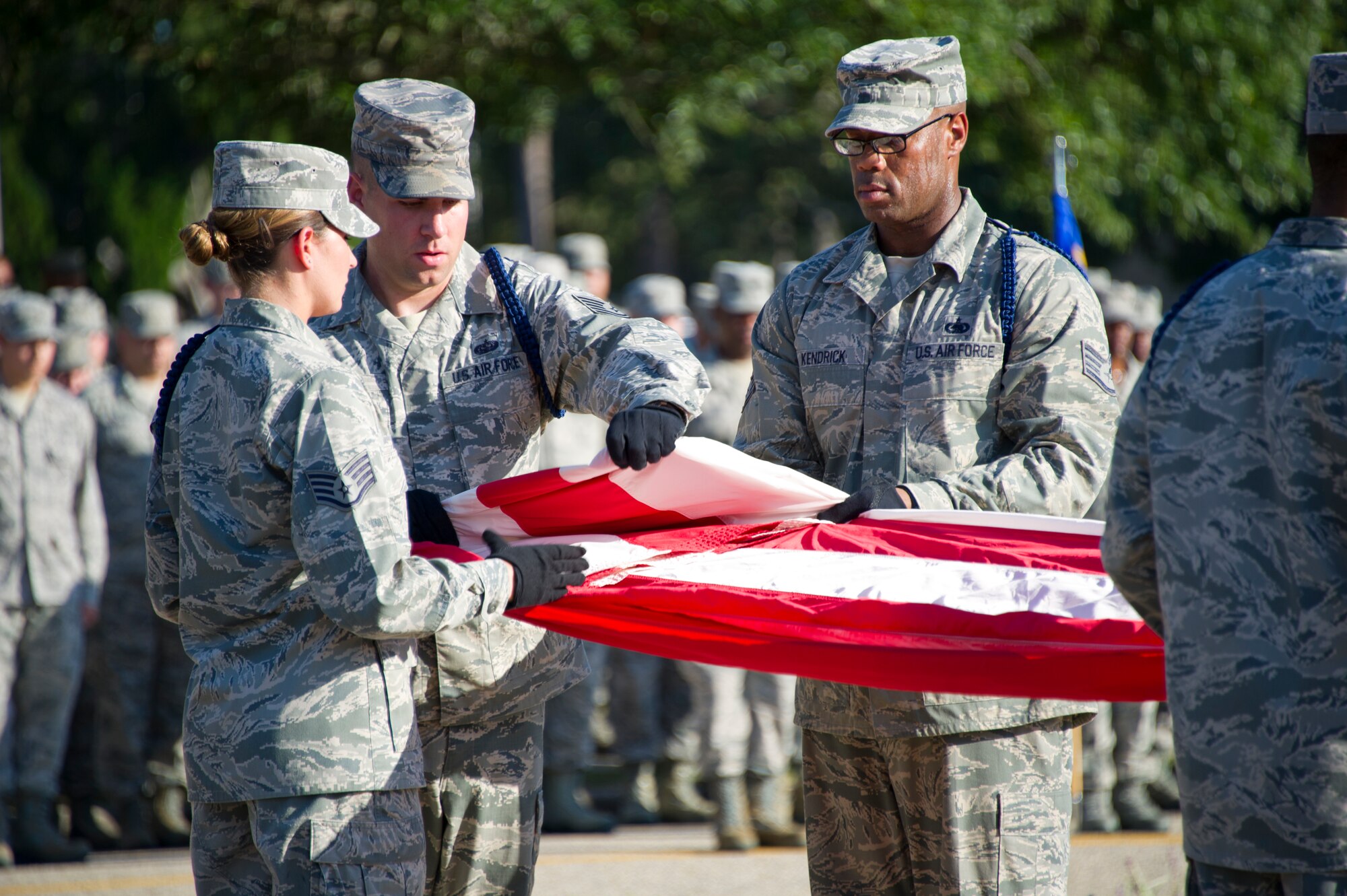 Tech. Sgt. Kyle Mullen, 81st Training Group military training leader, folds the U.S. flag with the assistance of Staff Sgts. Victoria Brady, 338th Training Squadron MTL, and Issac Kendrick, 336th Training Squadron MTL, during a retreat ceremony Sept. 11, 2013, Keesler Air Force Base, Miss. The ceremony honored those who lost their lives during the 9/11 attacks.  (U.S. Air Force photo by Adam Bond)