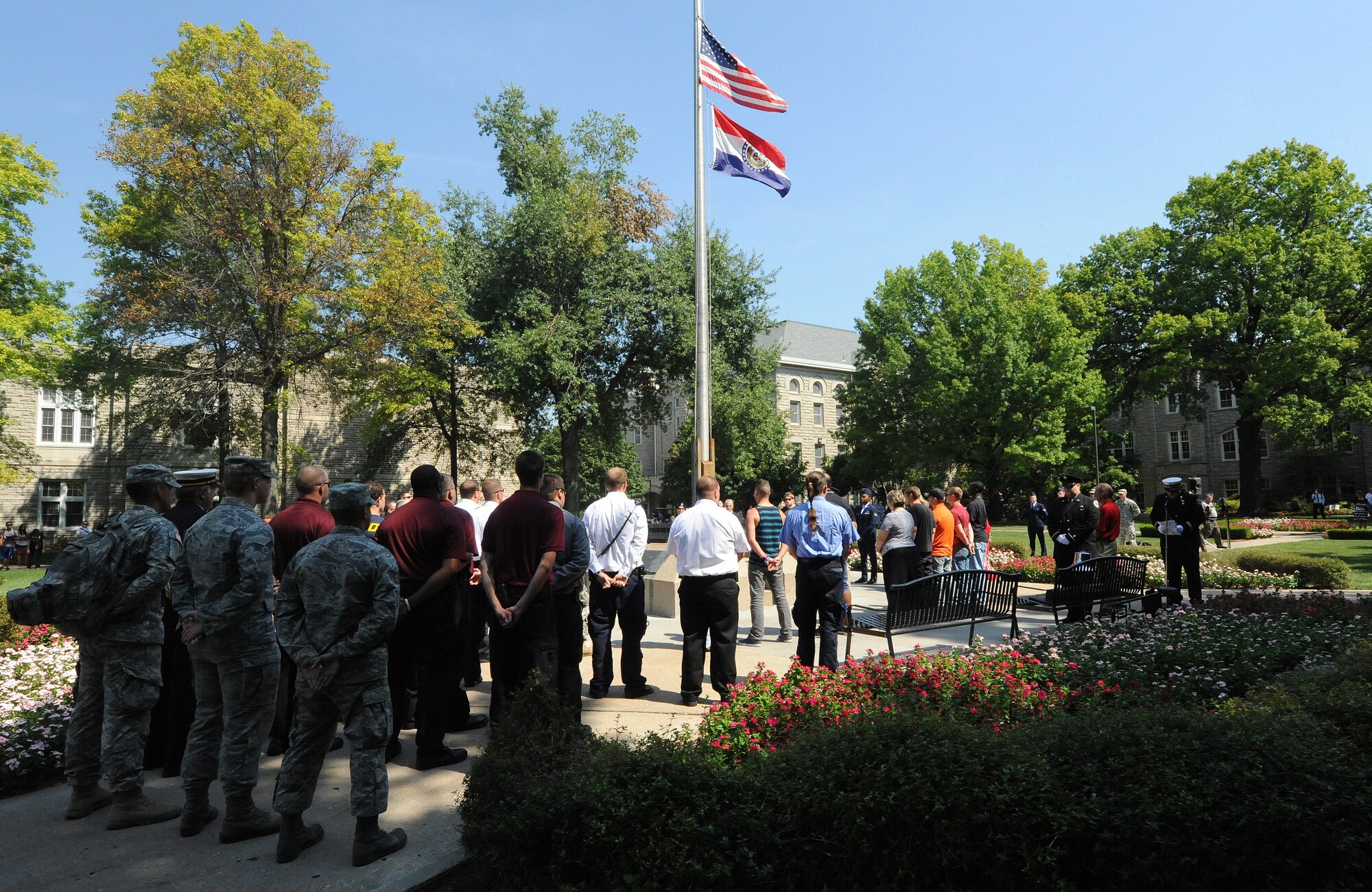 Civilians and Service members from the U.S. Air Force and U.S. Army gather around the flagpole as the American flag is lowered to half-staff at the University of Central Missouri in Warrensburg, Mo., Sept. 11, 2013. It is customary for the American flag to be lowered to half-staff on Sept. 11 to pay tribute to those who died during the World Trade Center and Pentagon terrorist attacks on Sept. 11, 2001. (U.S. Air Force photo by Staff Sgt. Nick Wilson/Released)