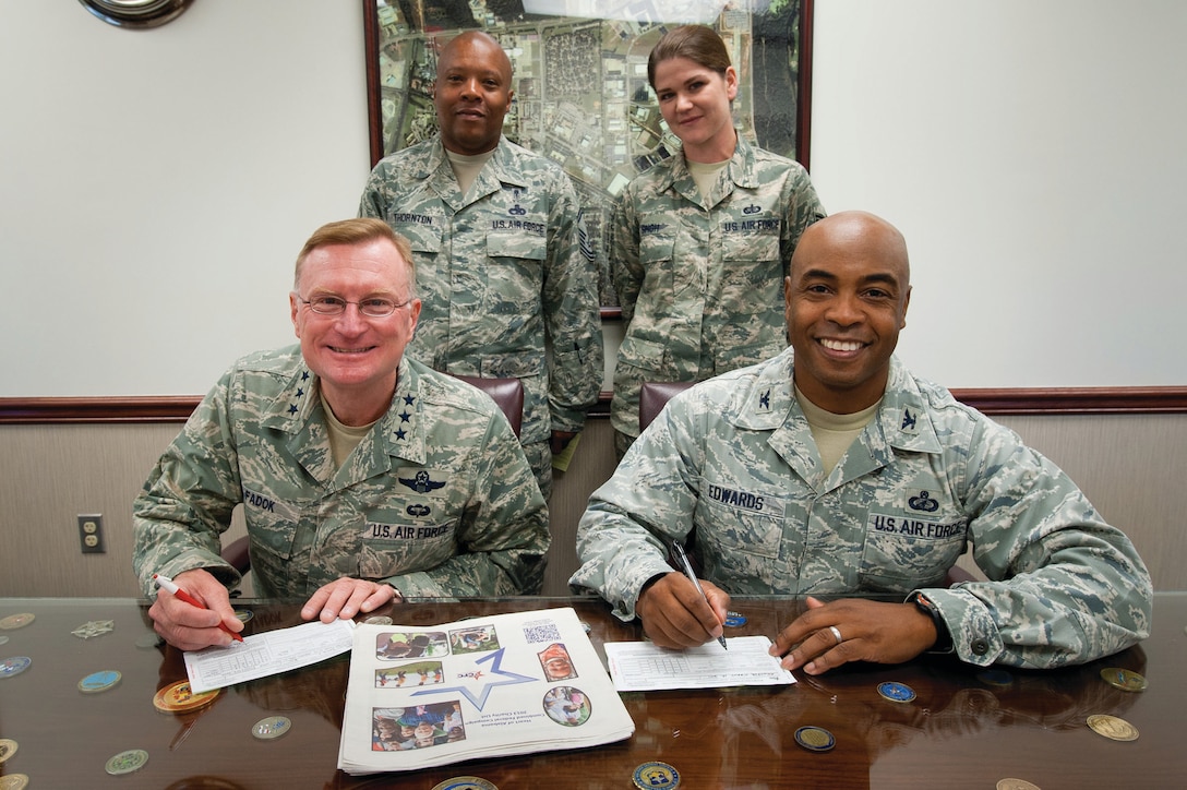 Air University Commander and President Lt. Gen. David Fadok, left, and 42nd Air Base Wing Commander Col. Trent Edwards sign their Combined Federal Campaign pledge forms Monday. Also shown are the CFC campaign chairs for Air University and 42nd Air Base Wing, Senior Master Sgt. Arthur Thornton and Staff Sgt. Heather Singh. (U.S. Air Force photo by Melanie Rodgers Cox)