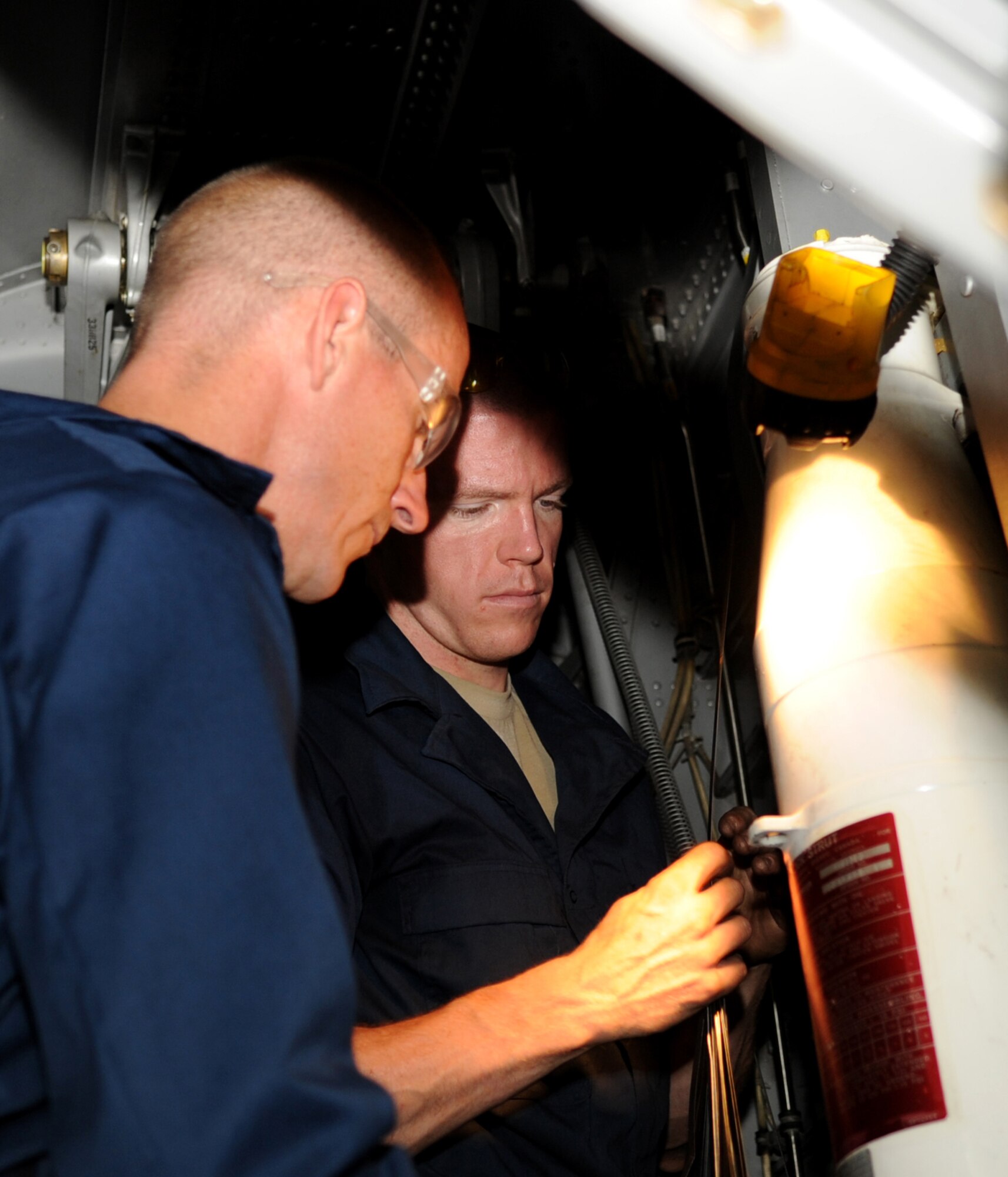 U.S. Air Force Senior Airman Sean Hopkins, right, works under the wing of a C-130J with Col. Jeffrey Brown, 317th Airlift Group commander, Sept. 6, 2013, at the Global Reach for America hangar on Dyess Air Force Base, Texas. Hopkins is a repair and reclamation journeyman on the C-130’s at the 317th Maintenance Squadron. He spent two hours working alongside Brown, showing him how to rig main landing gear track shoes. (U.S. Air Force photo by Senior Airman Shannon Hall/Released)