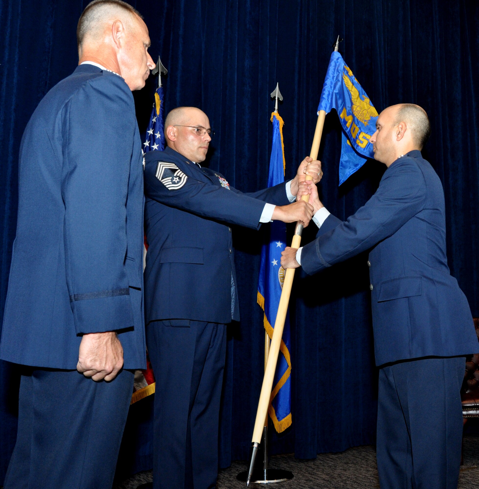 During the 433rd Maintenance Operation Squadron's September's Unit Training Assembly, Col. Charles Combs, 433rd Maintenance Group Commander (left), stands ready as Chief Master Sgt. Anthony Rittwager, 433 MOS Superintendent, passes off the 433rd MOS’ guidon to MOS Commander, Lt. Col. David Rodriquez, during an inactivation ceremony on Joint Base San Antonio-Lackland, Texas Sept. 9 at the Inter-American Air Forces Academy’s auditorium. 