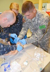 Interservice Respiratory Therapy Program students Navy Petty Officer 1st Class Eugene Nixdorf, Navy Hospitalman Shawnee Van Damme and Army Spc. Brandon Rhodes apply a nasal continuous positive airway pressure device on an infant patient simulator during a practical exercise for the RESP 110 Neonatal and Pediatric Respiratory Care course. (Air Force photo by Lori Newman, JBSA-Fort Sam Houston Public Affairs)