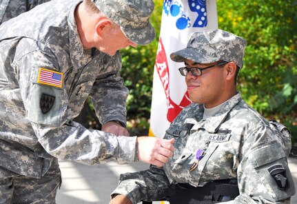 Lt. Gen. Robert P. Lennox, principal deputy director of Cost Assessment and Program Evaluation, presents the Purple Heart medal to Spc. Giovanni S. Cook during a ceremony at the Warrior and Family Support Center Sept. 6. Cook was injured July 13 when his vehicle was struck by an improvised explosive device while conducting a mounted patrol in Afghanistan. (Army photo by Robert Shields, Brooke Army Medical Center Public Affairs)