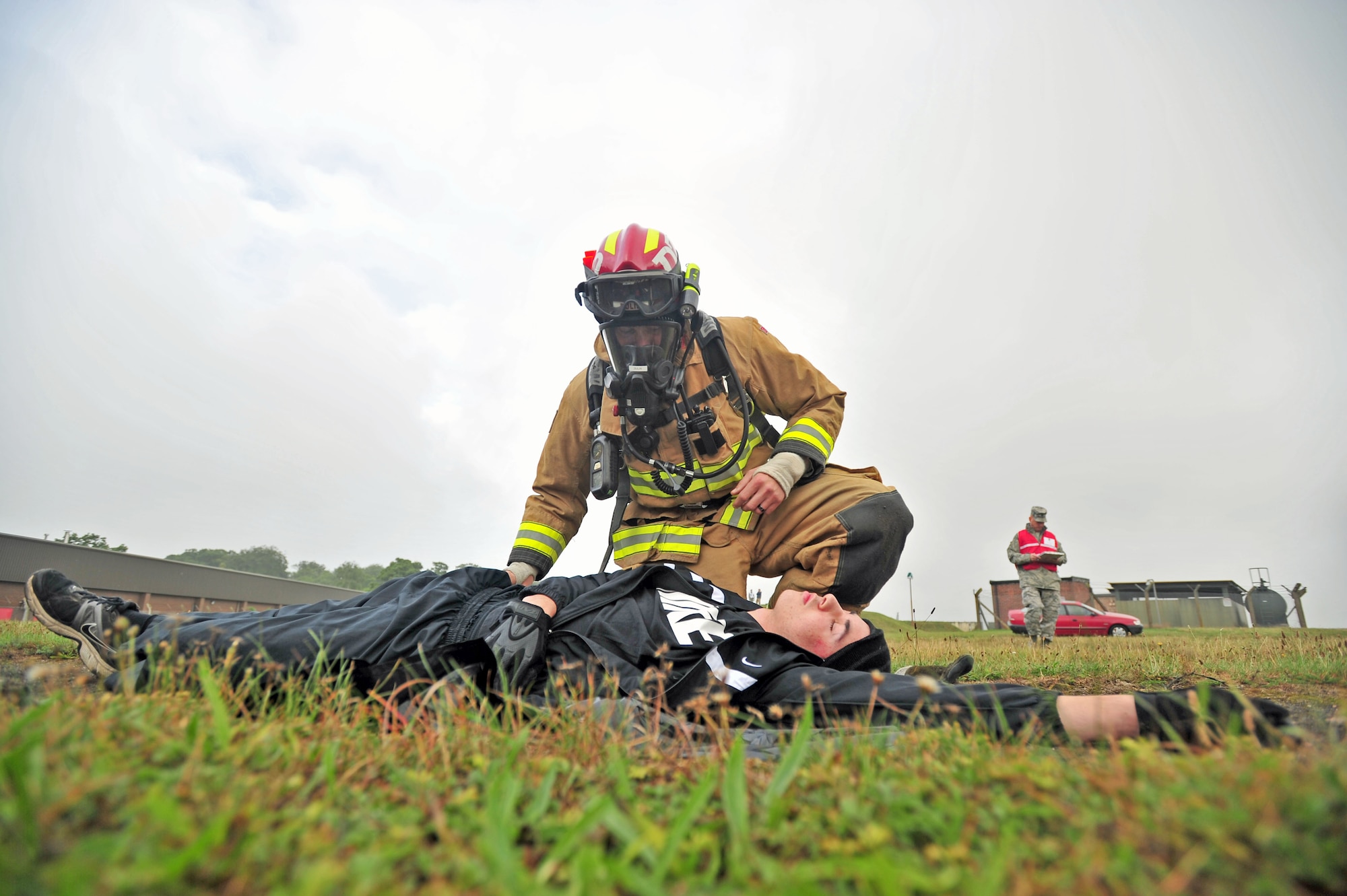 U.S. Air Force Staff Sgt. Kyle Dublin, kneeling, 100th Civil Engineer Squadron Fire Department firefighter, surveys a simulated casualty for injuries during an operational readiness inspection Sept. 12, 2013, on RAF Mildenhall England. The exercise tested firefighters' ability to contain a fuel spill. The casualty "passed out" from inhaling fuel fumes. (U.S. Air Force photo by Senior Airman Christine Griffiths/Released)