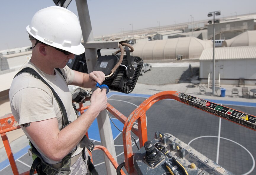 U.S. Air Force Senior Airman Mason Mercer, 380th Expeditionary Civil Engineer Squadron electrical systems journeyman, tapes the end of a wire for a new light emitting diode fixture being place on a basketball court at an undisclosed location in Southwest Asia Sept. 11, 2013. The electrical systems shop is in the process of replacing older outdoor lighting with new light emitting diode and solar powered lights. Mercer calls Punta Gorda, Fla., home and is deployed from Fairchild Air Force Base, Wash. (U.S. Air Force photo by Staff Sgt. Jacob Morgan)